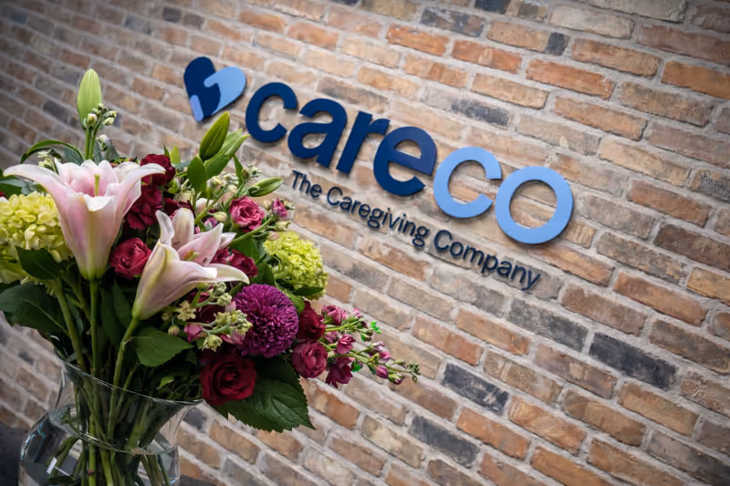 CareCo sign on brick wall with a colorful bouquet displayed in foreground.
