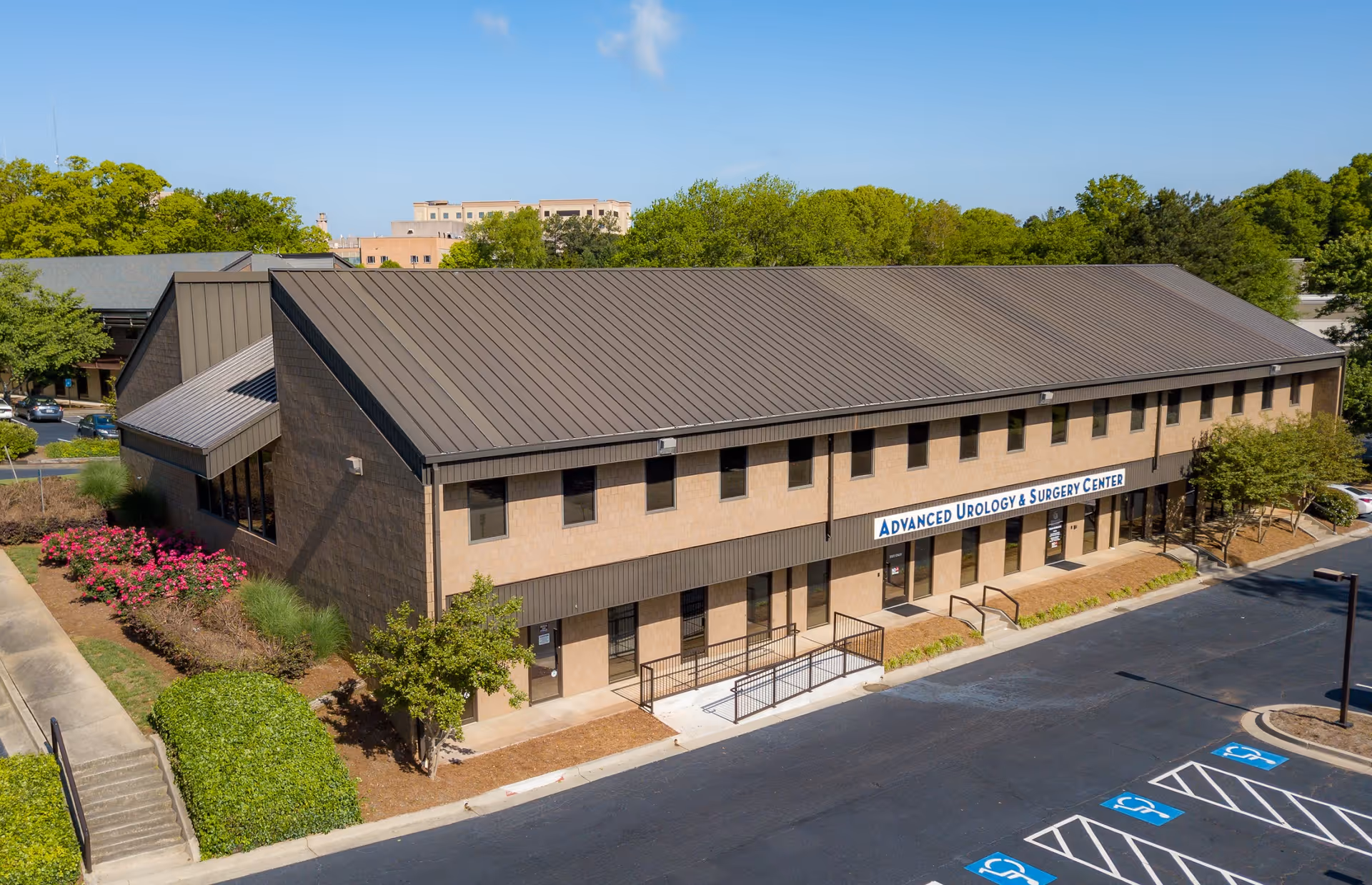 Aerial view of a two-story beige medical building labeled Advanced Urology & Surgery Center.