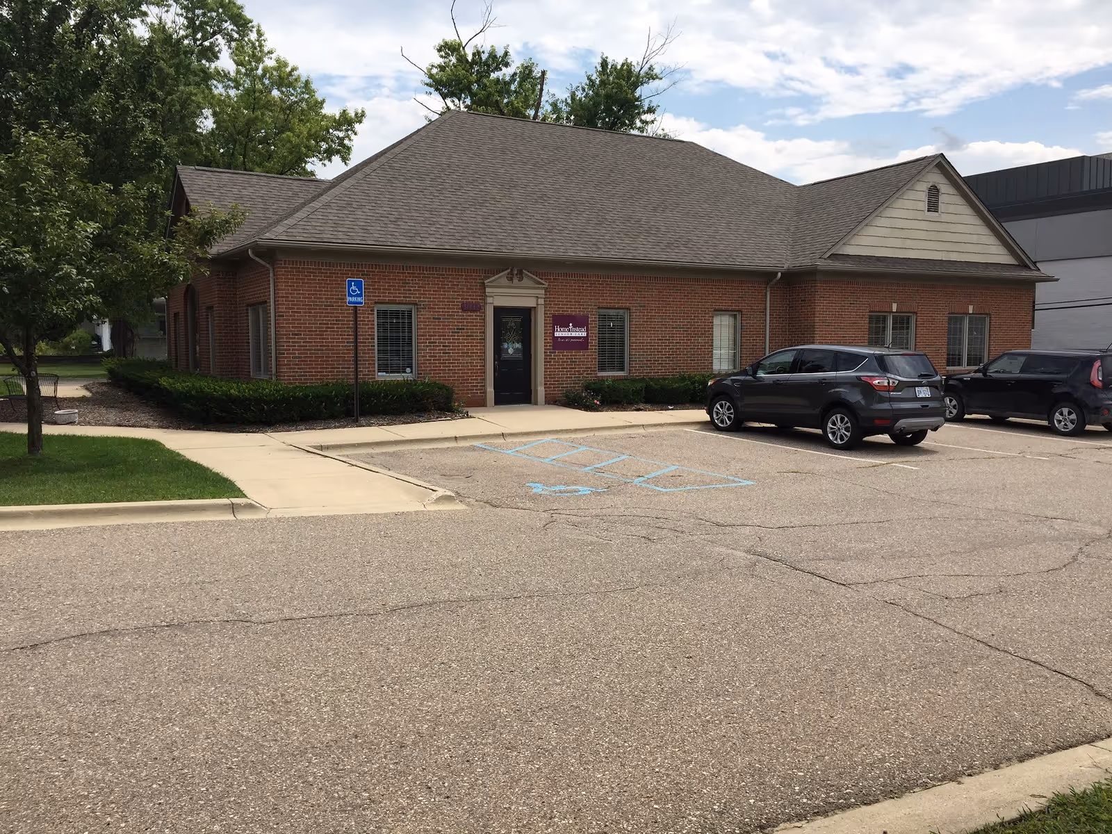 Brick facade senior living facility exterior with a parking lot and accessible entrance.