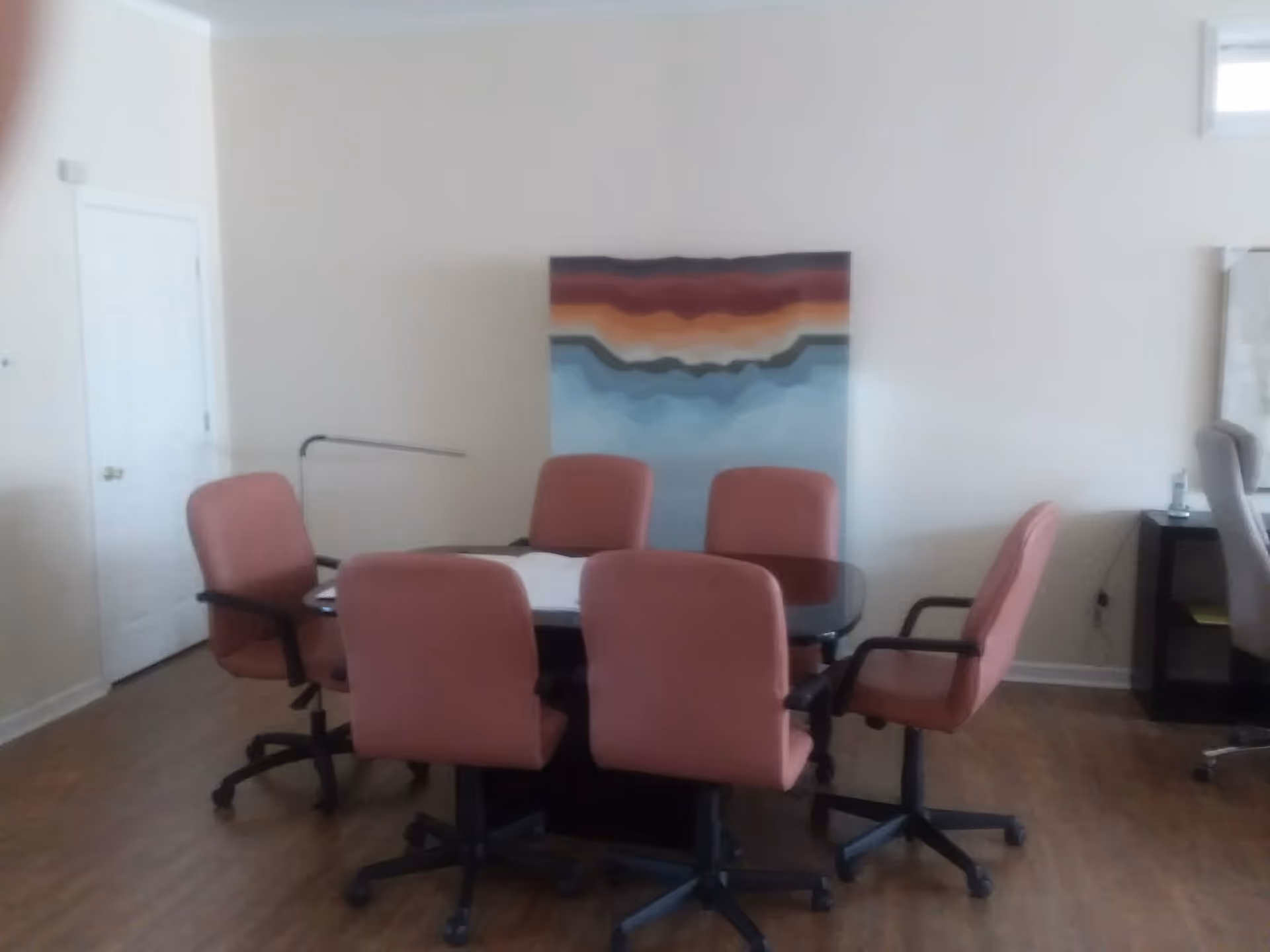 Meeting room with pink chairs arranged around a central table in a bright interior.