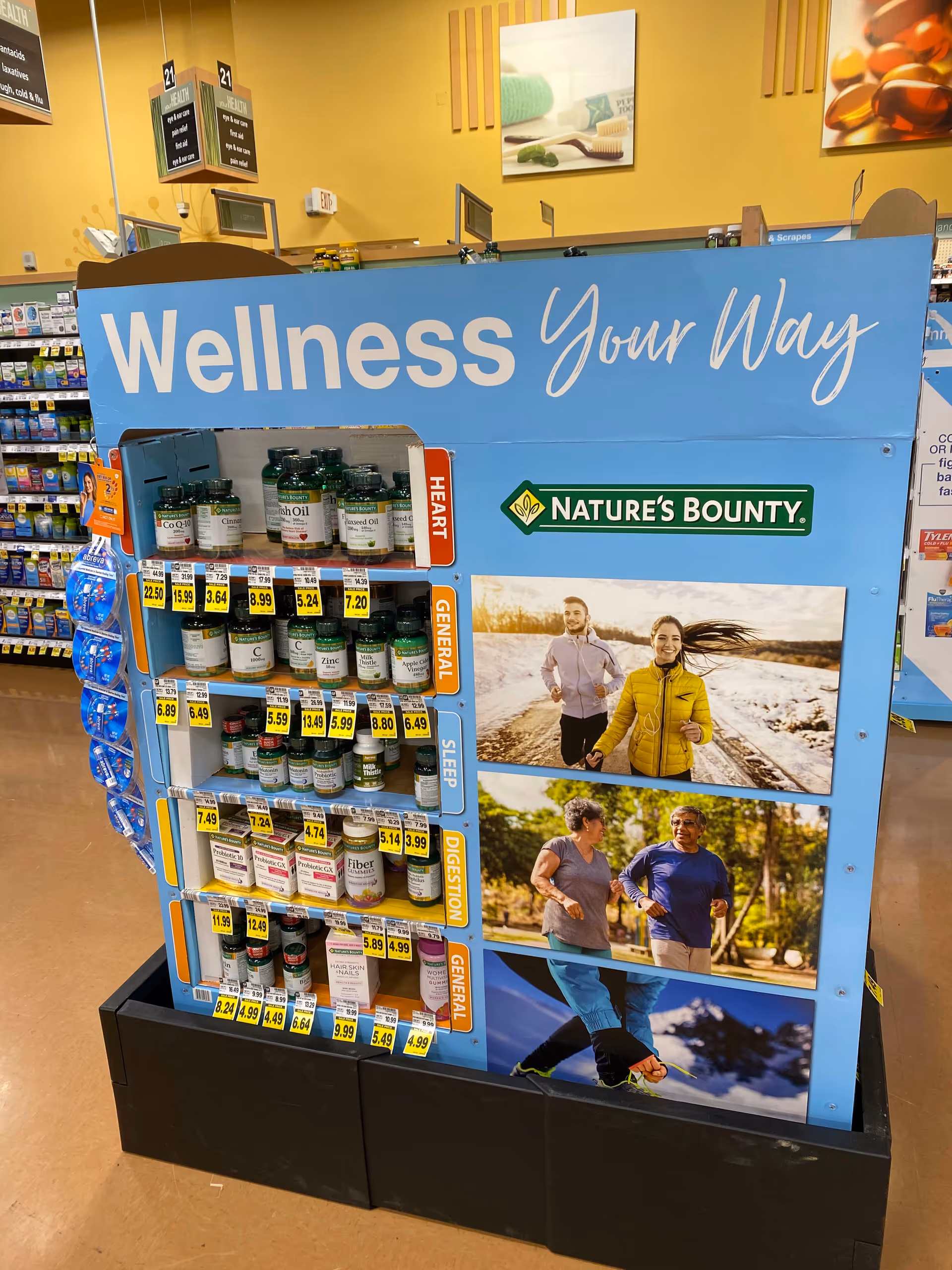 Blue wellness display with supplement shelves and Nature's Bounty photos in a Kroger pharmacy.