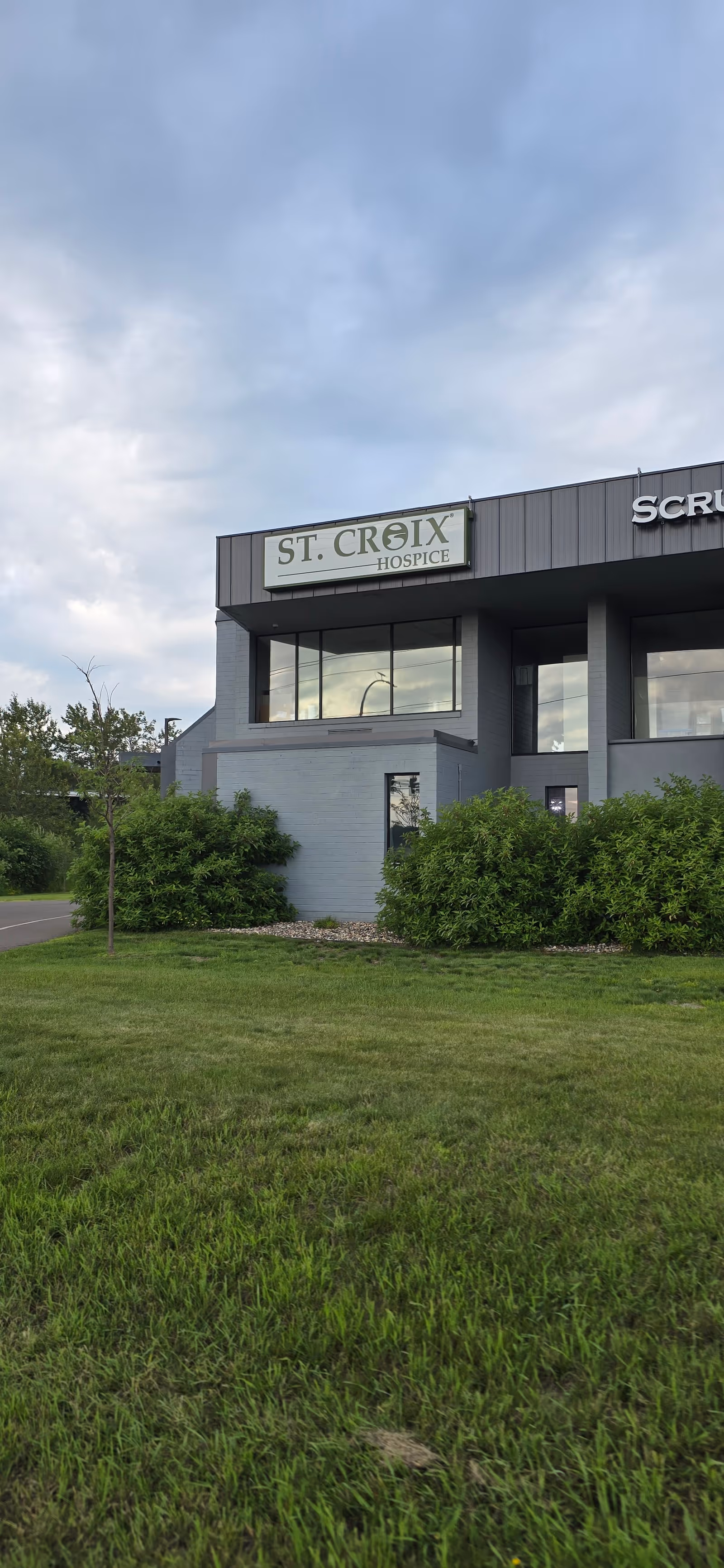 Exterior view of a gray building with St. Croix Hospice signage and green landscaping.