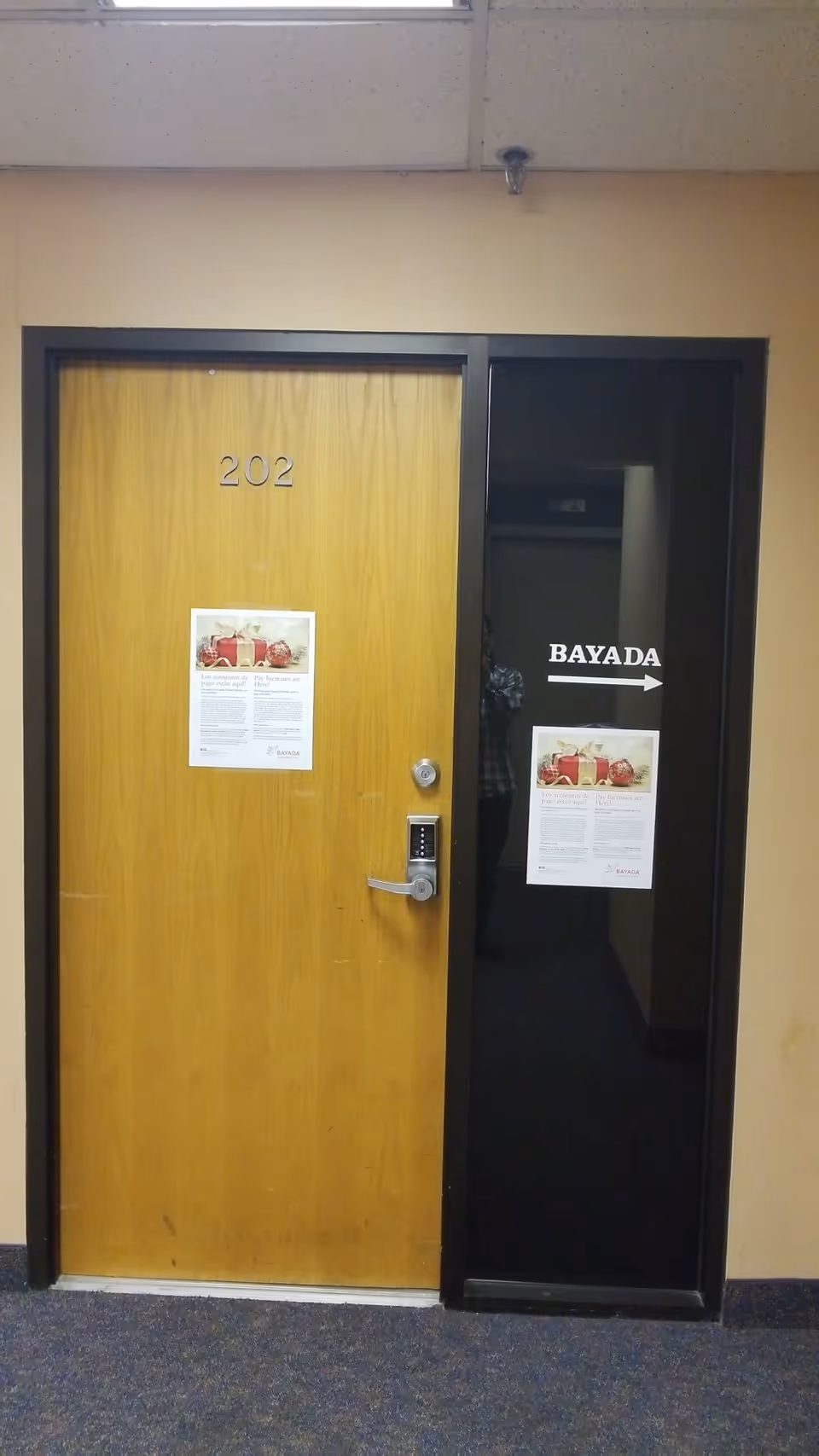 Wooden door labeled 202 beside a black glass doorway with BAYADA sign.