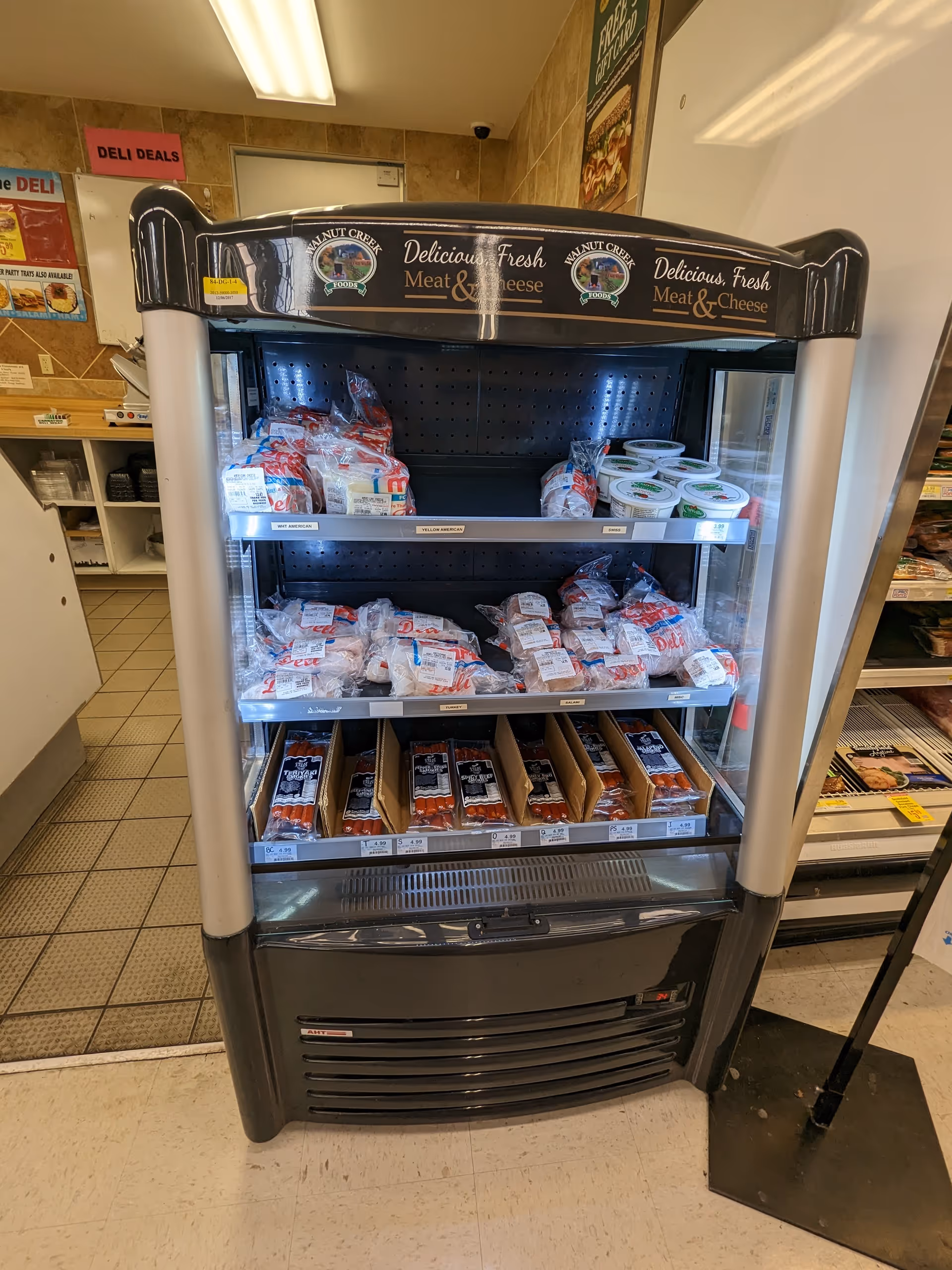 Interior view of a deli display cooler stocked with meat and cheese packages.