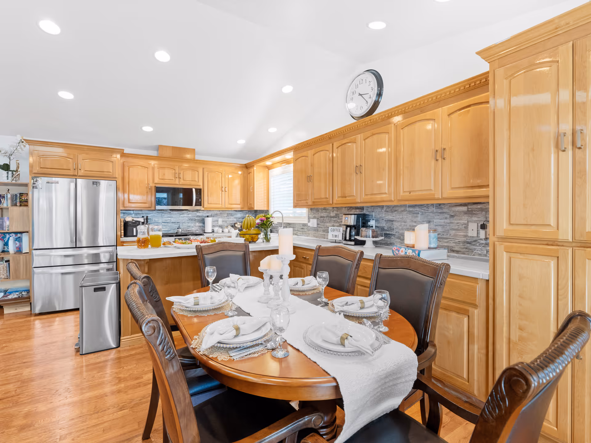 Bright kitchen with wooden cabinets and a round dining table set for a meal.