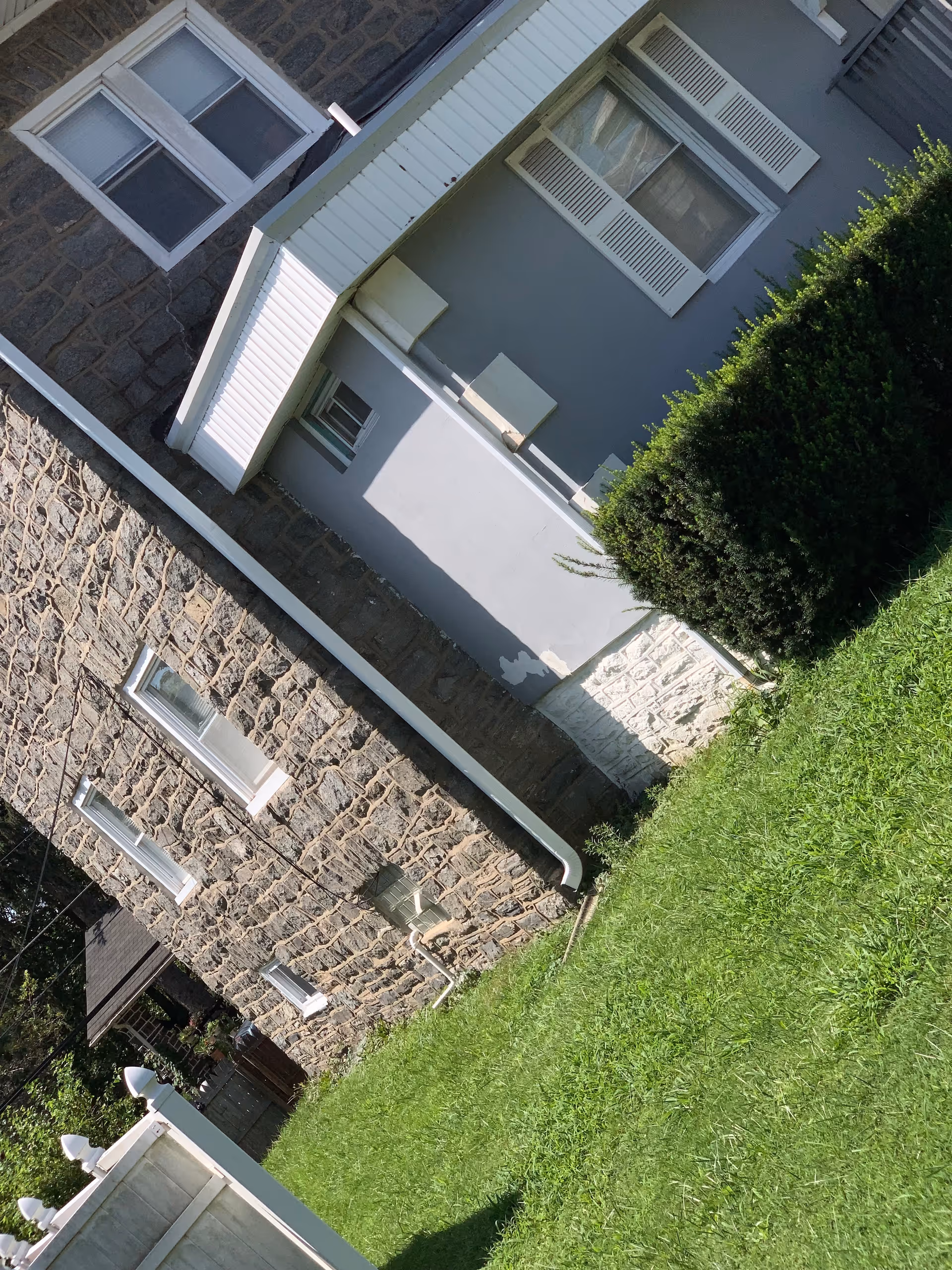 Exterior view of a stone building with windows and green lawn.