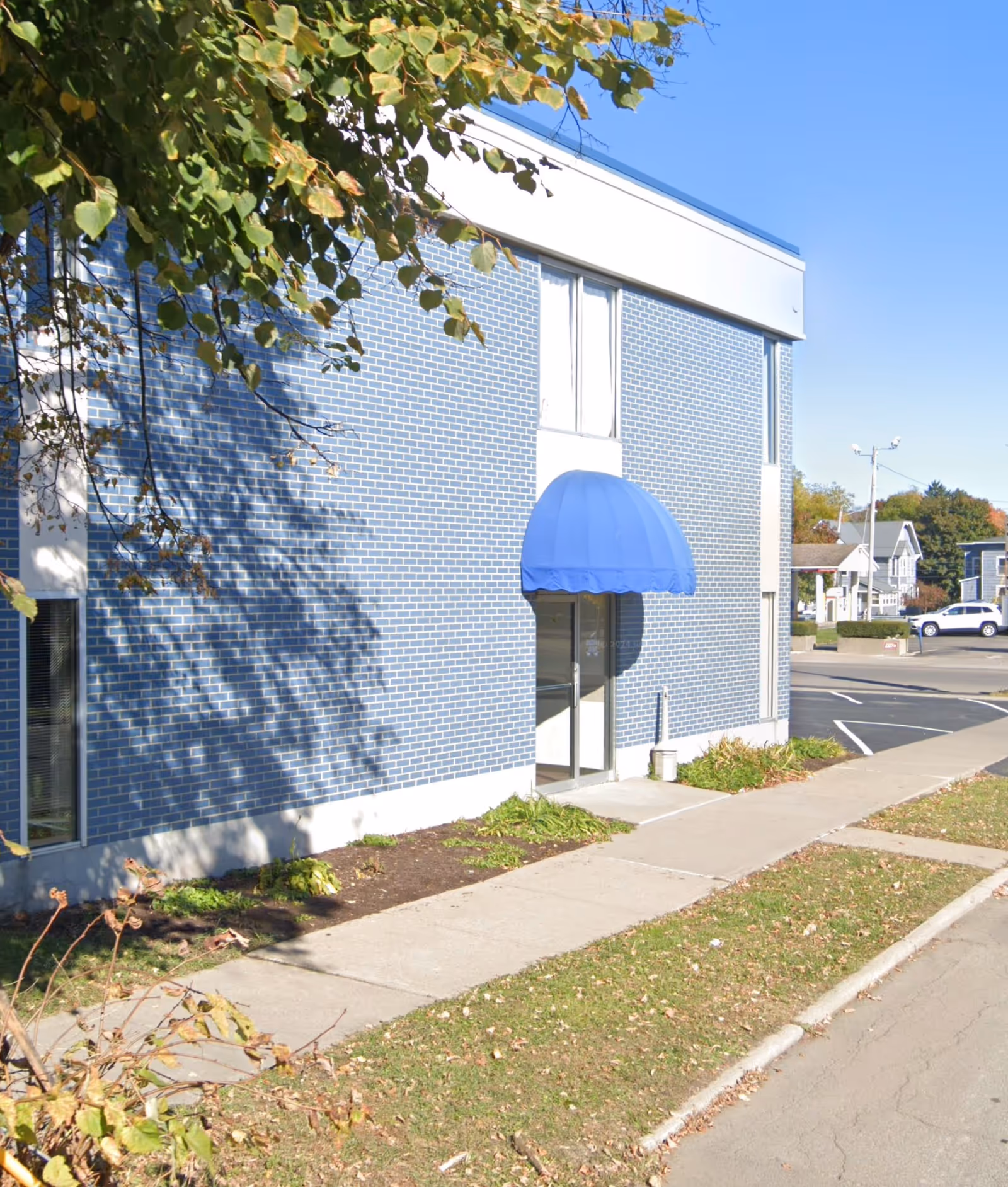 Blue brick Home Instead exterior with blue entrance canopy and sidewalk.