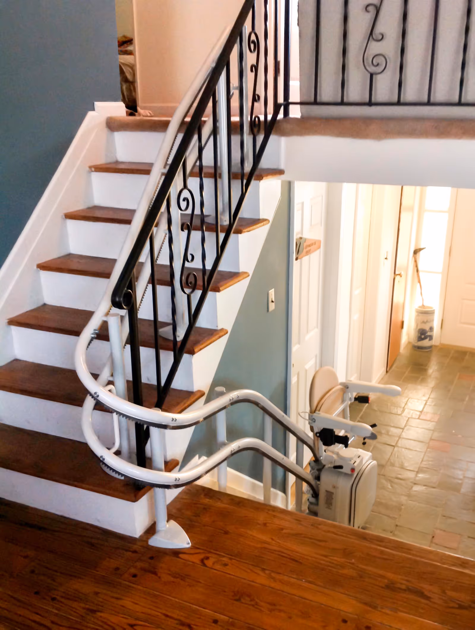 Interior stairway with wooden steps and a mounted stair lift beside the railing.