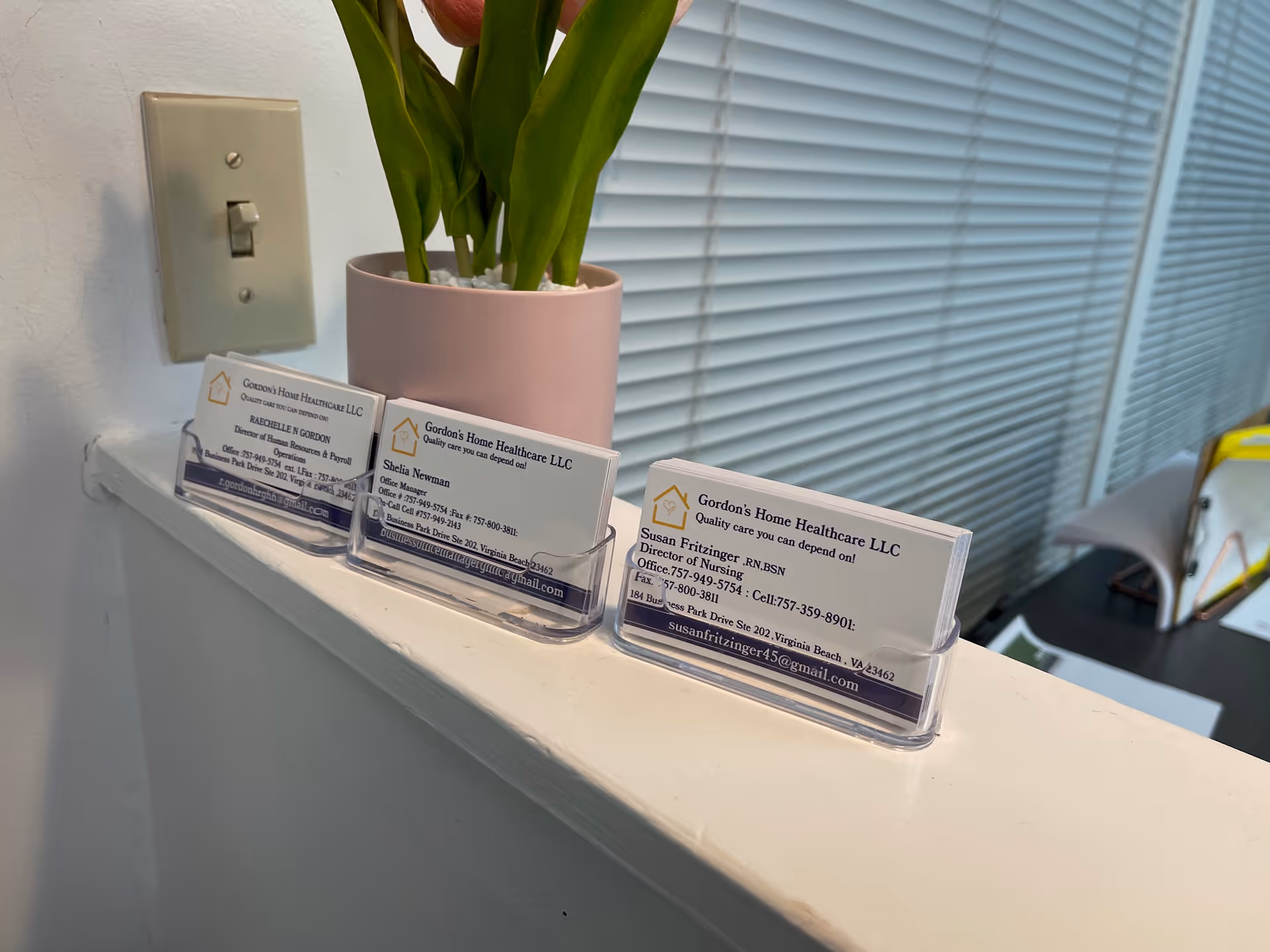 Reception counter with Gordon's Home Healthcare business cards and a pink potted plant.