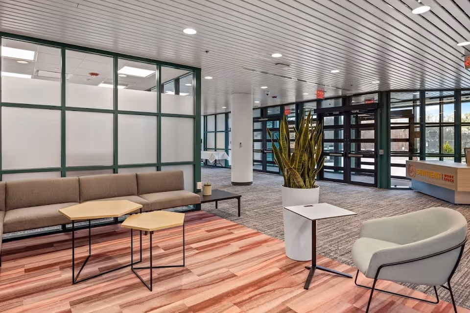 Modern facility lobby with seating, a large plant, and glass partition walls.