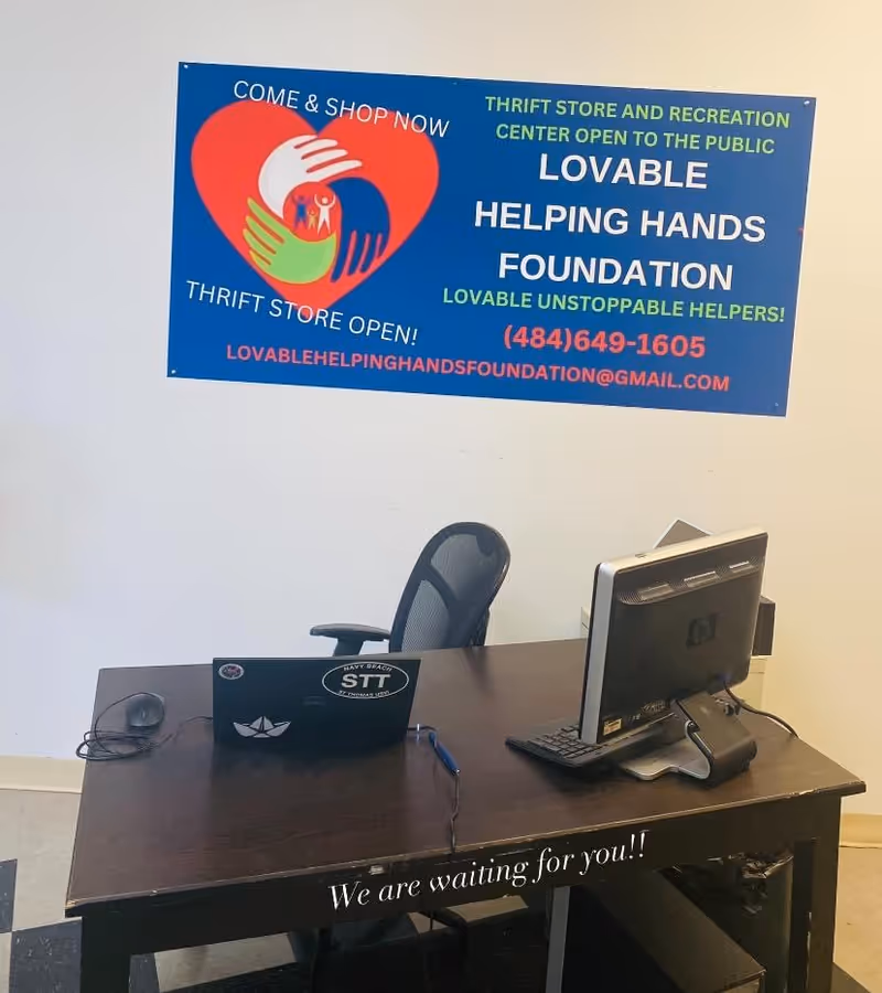 Interior office with desk, computer, and a Lovable Helping Hands Foundation banner on the wall.