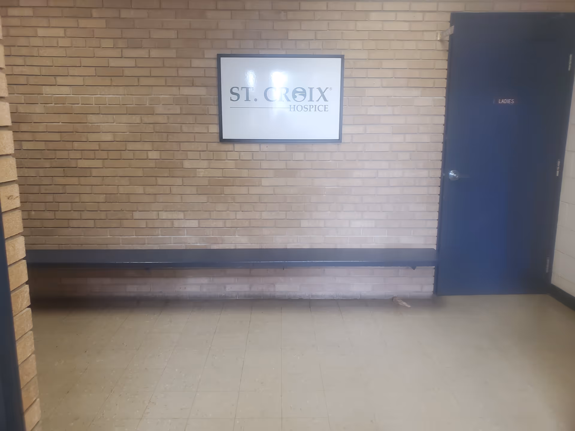 Interior brick hallway with a bench and a St. Croix Hospice sign