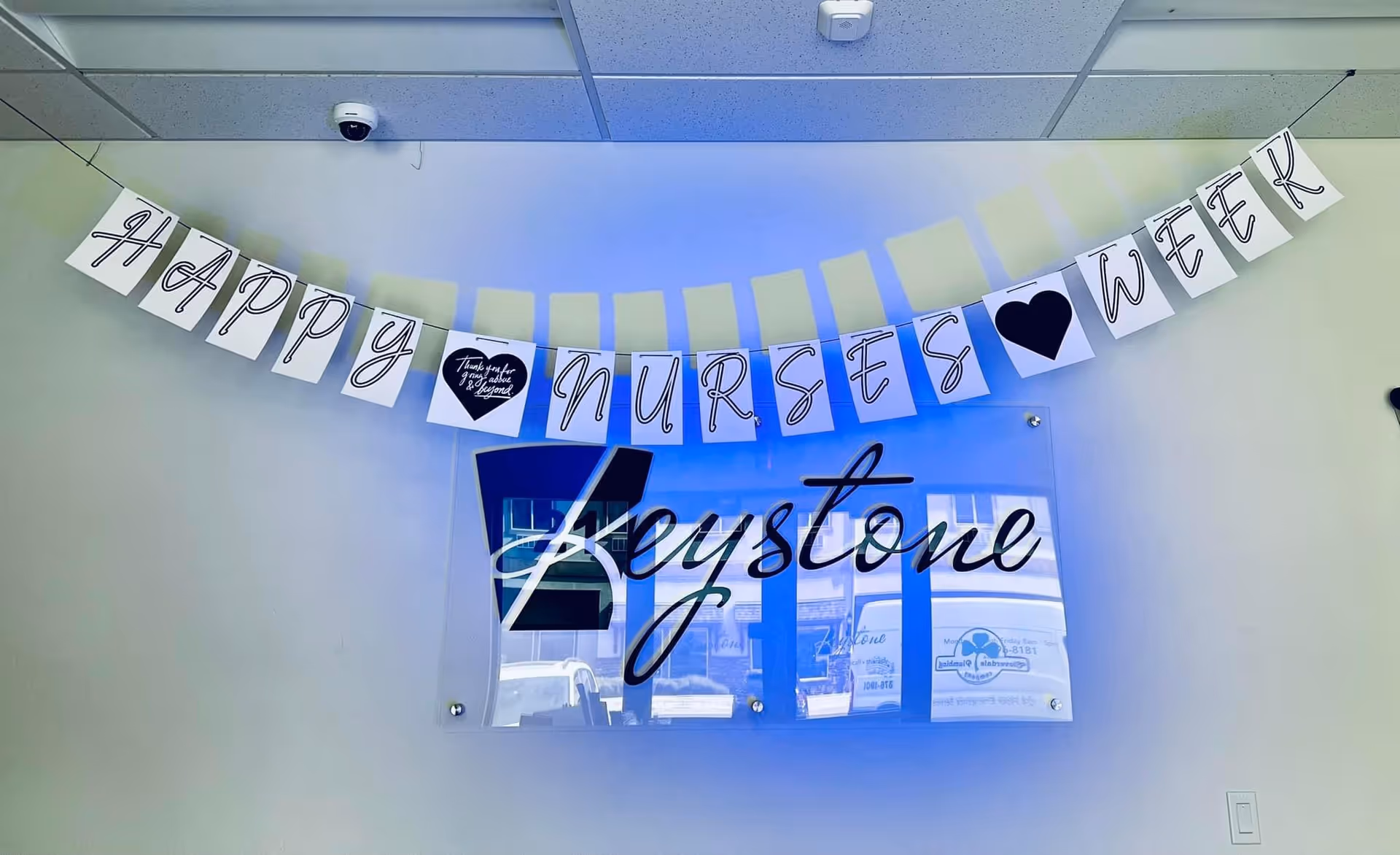 Indoor hallway with a Happy Nurses Week banner and Keystone sign.