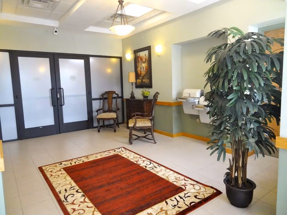 Lobby area with frosted glass doors, chairs, rug, plant, and wall art.