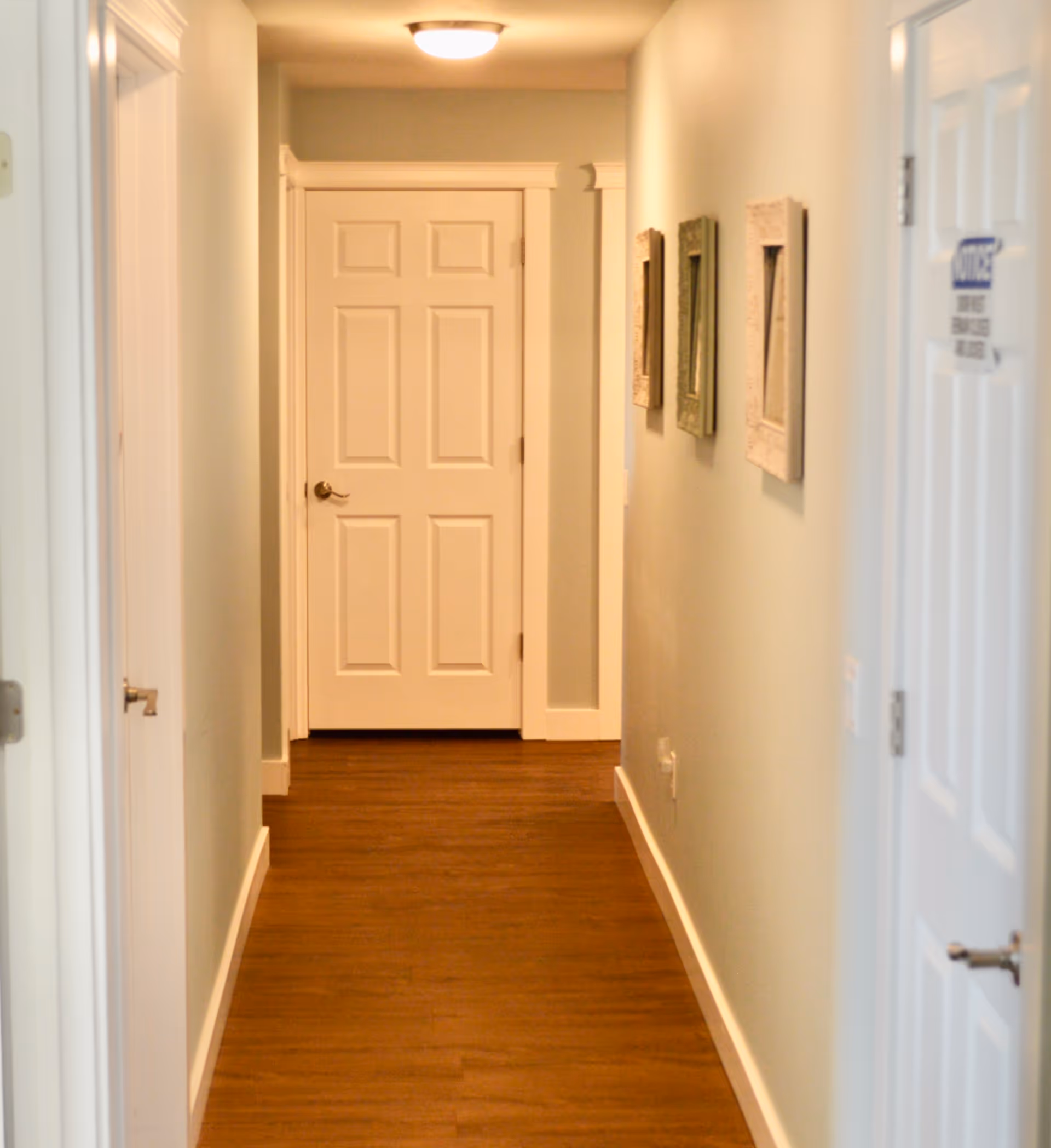 Long hallway in a senior living facility with closed doors and wall art.