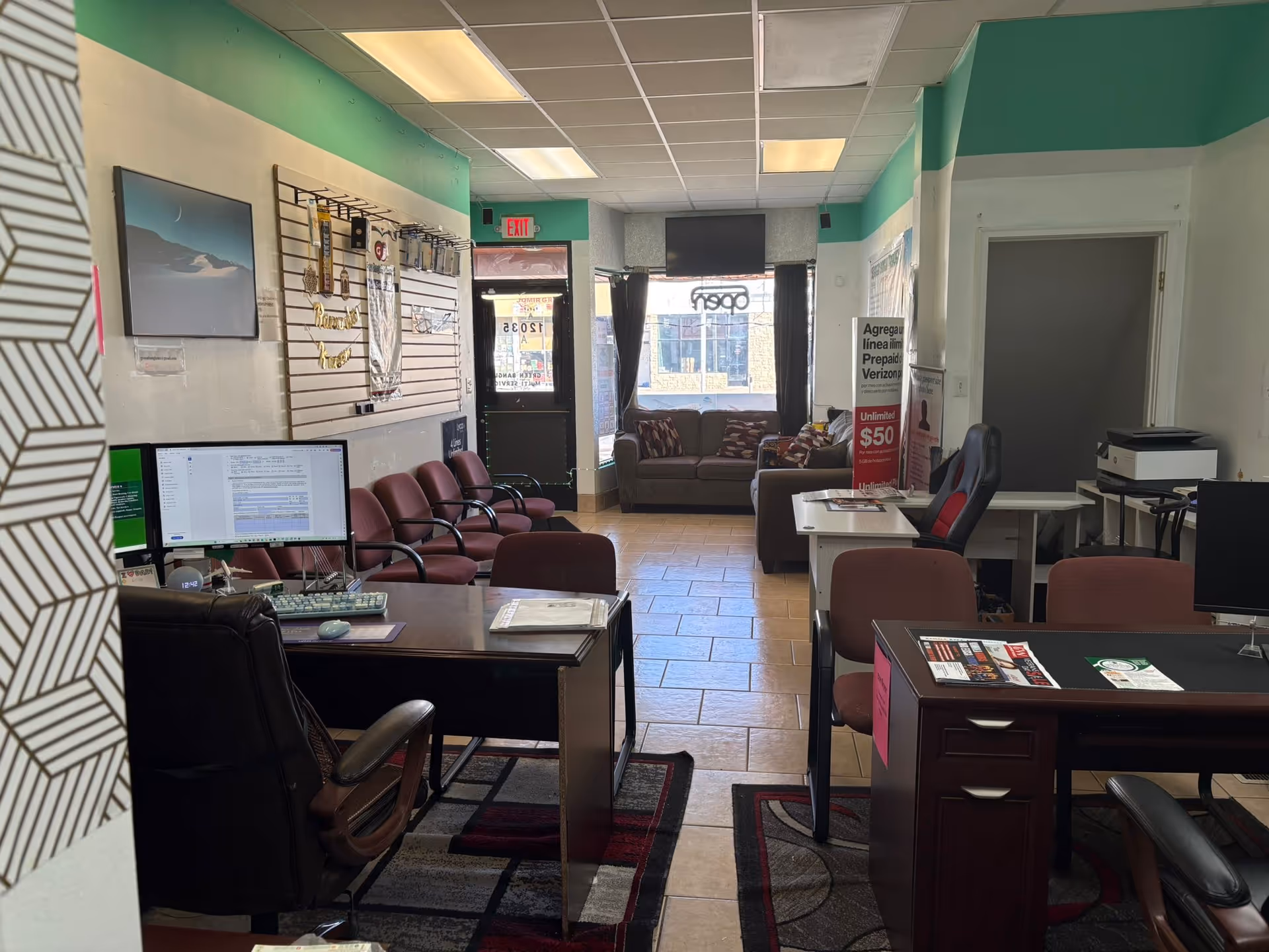 Interior office reception with desks, computers, chairs, and a waiting area.