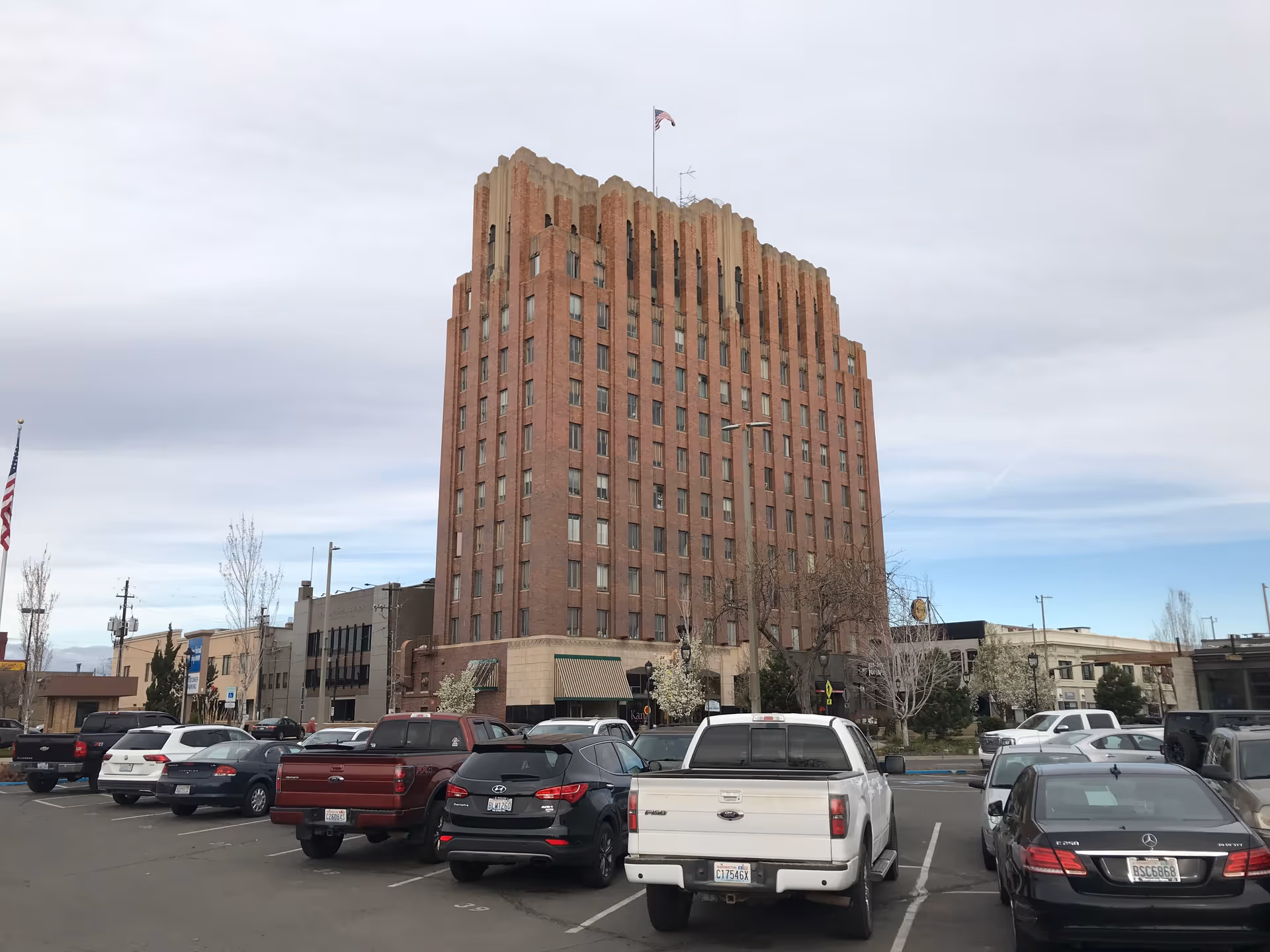 Tall brick building with a storefront base and a busy street parking lot.