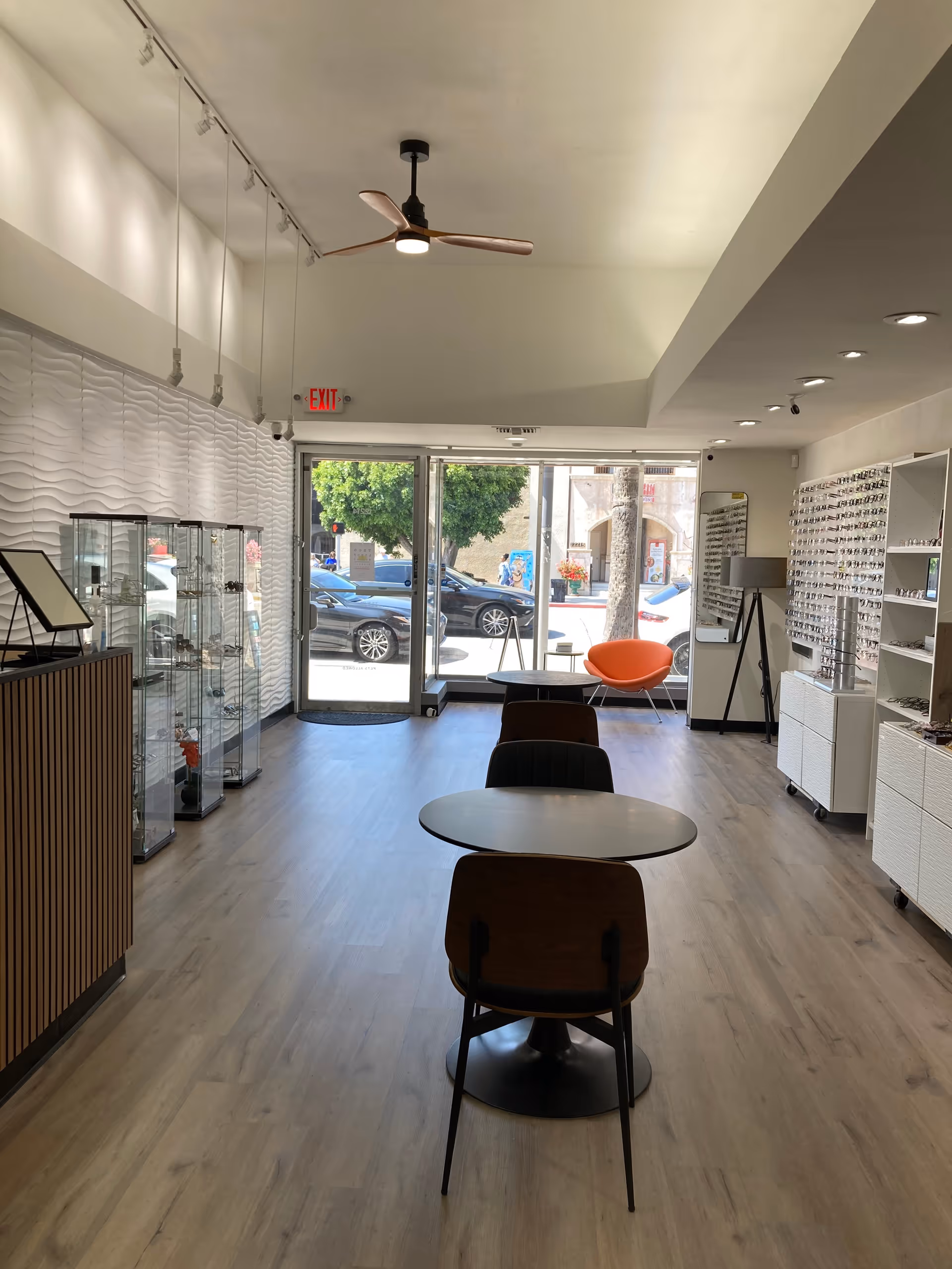 Interior of an optometry shop with eyeglass displays, tables, and seating.