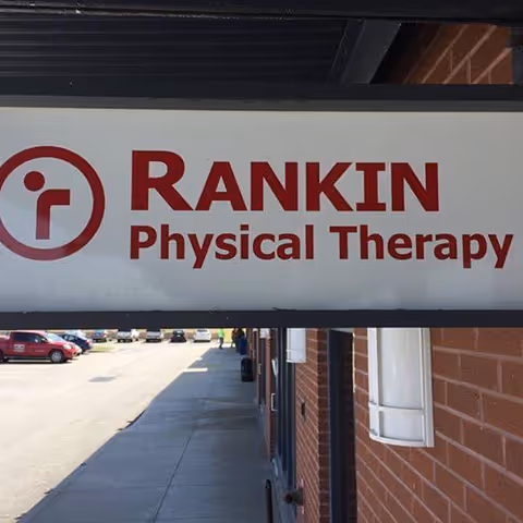 Overhead Rankin Physical Therapy sign on brick building exterior beside a sidewalk