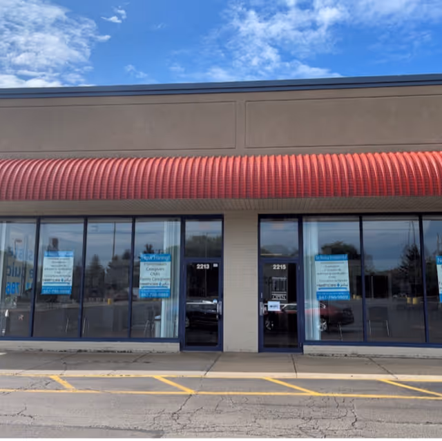 Exterior view of a medical facility storefront with glass windows and a red curved awning.