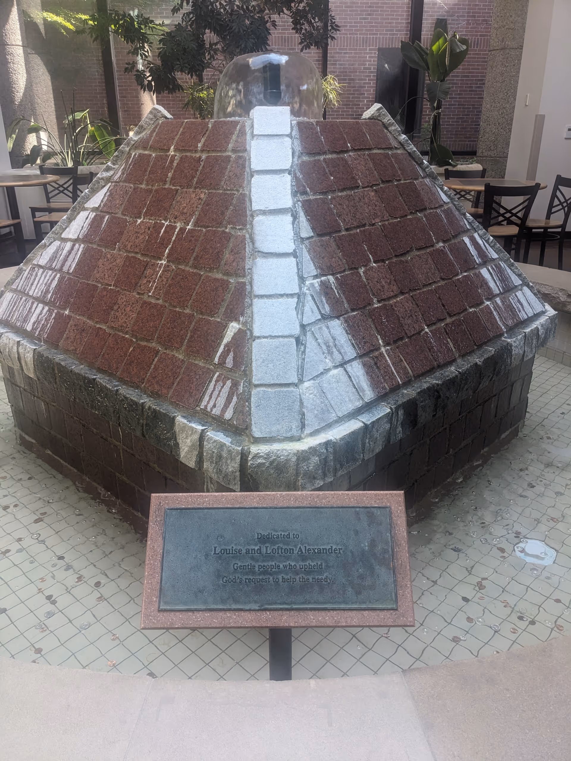 Stone pyramid fountain centerpiece with plaque in an indoor seating atrium