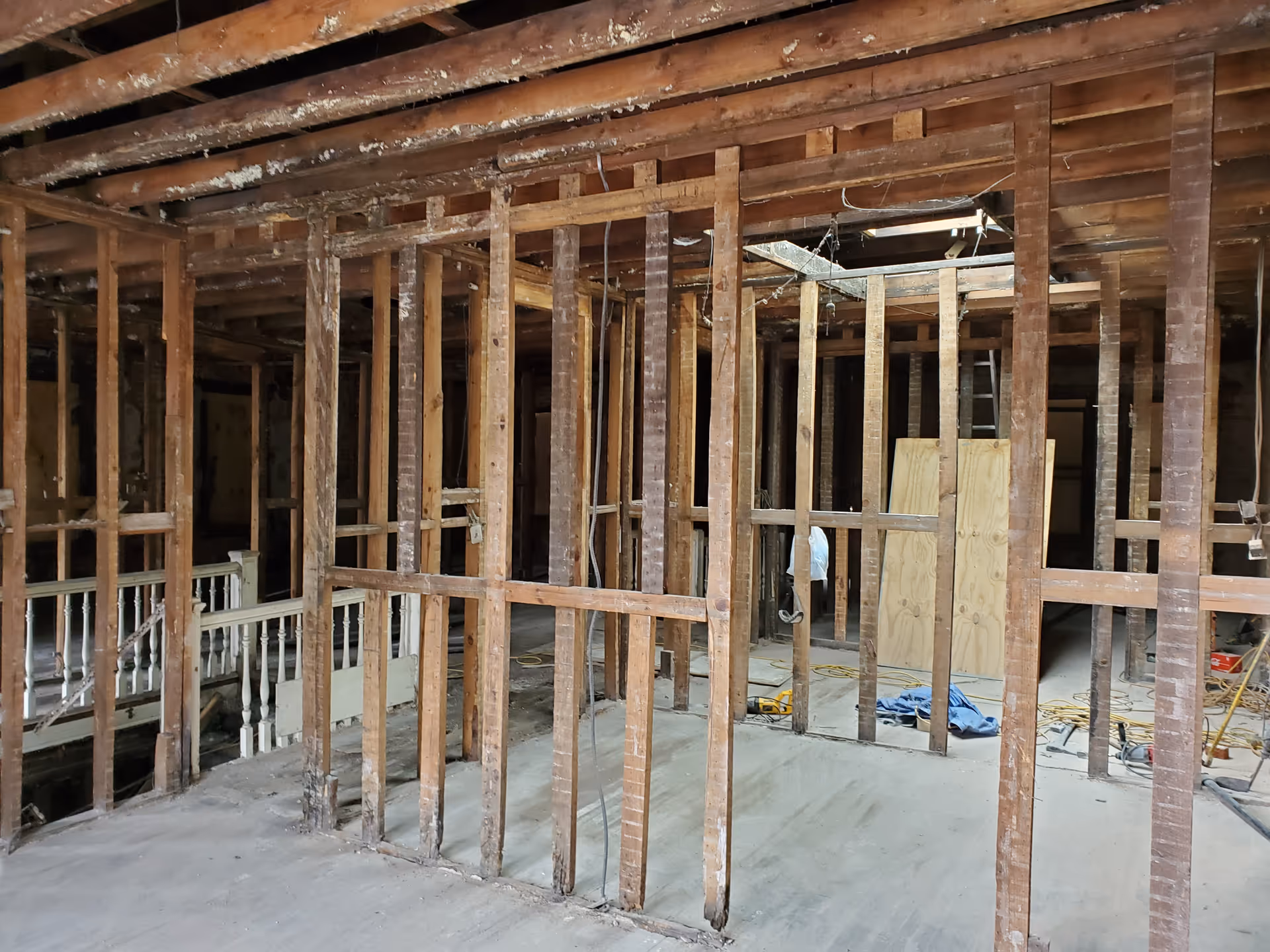 Unfinished interior with exposed wooden studs and construction debris during renovation.