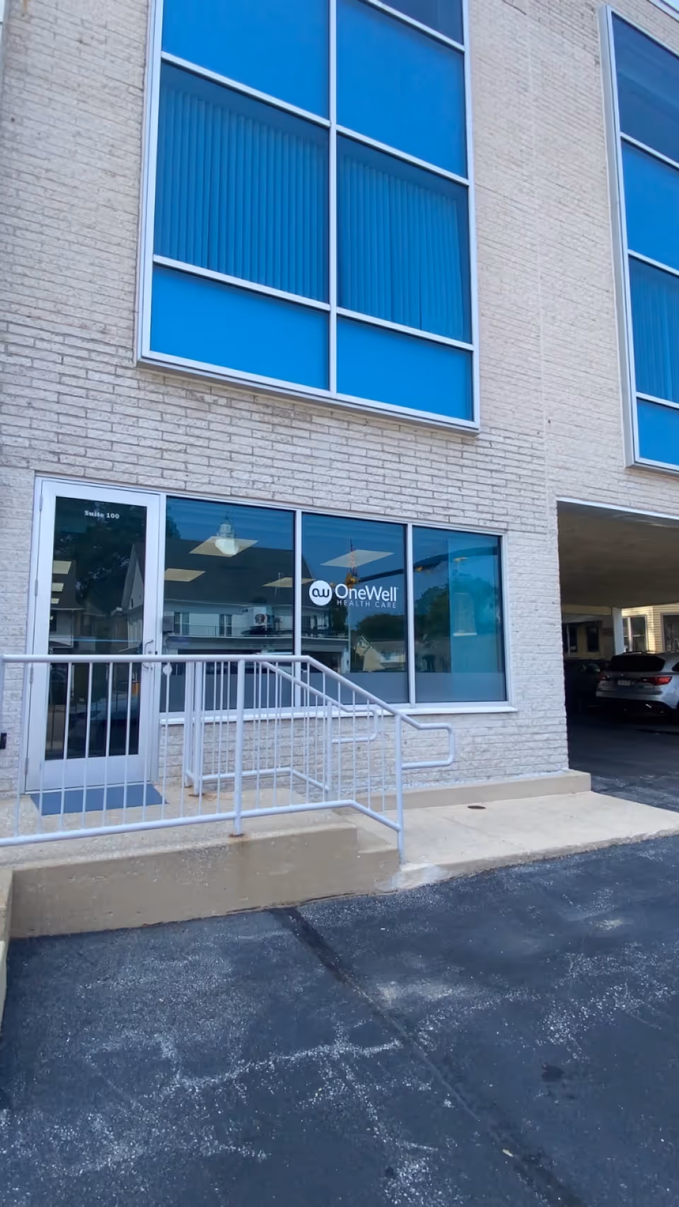 Exterior view of OneWell Health Care building with glass entrance and blue tinted windows.