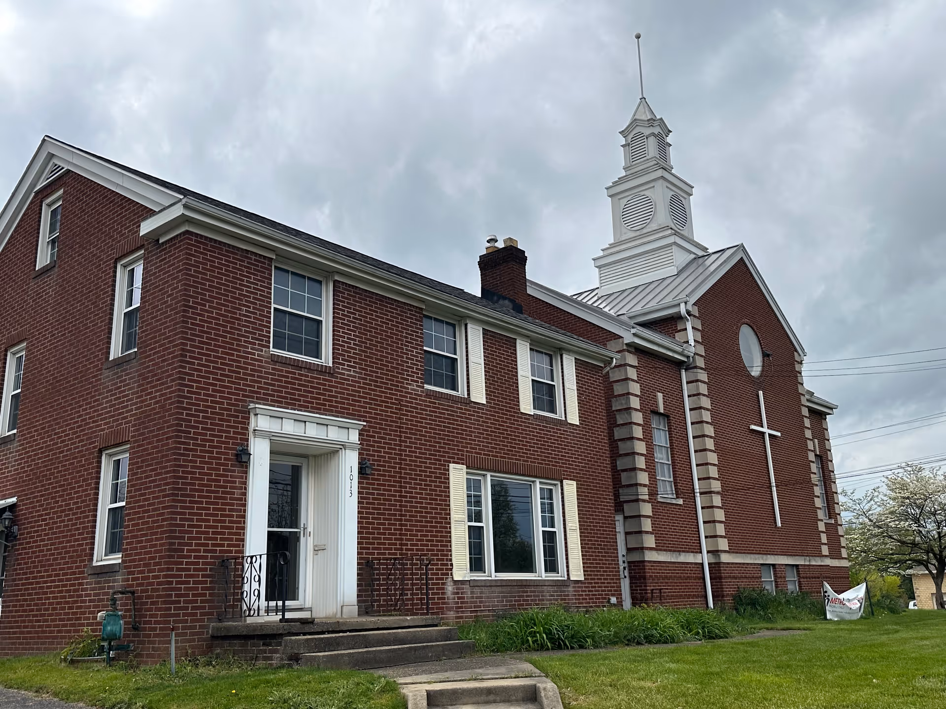 A brick senior living facility featuring a white steeple, cross, and manicured lawn.