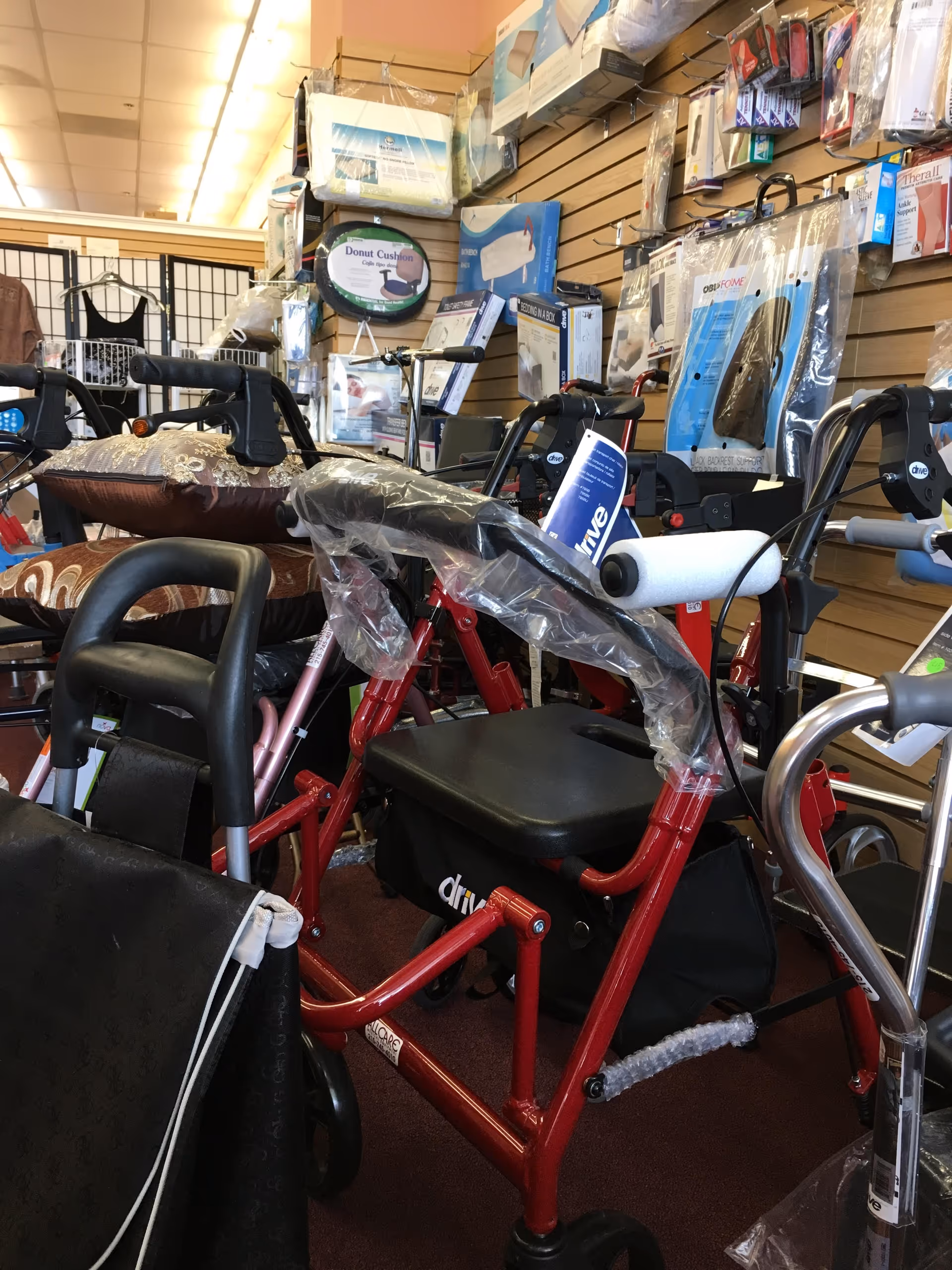 Inside a medical equipment store, assistive devices like walkers and a red mobility scooter on display.