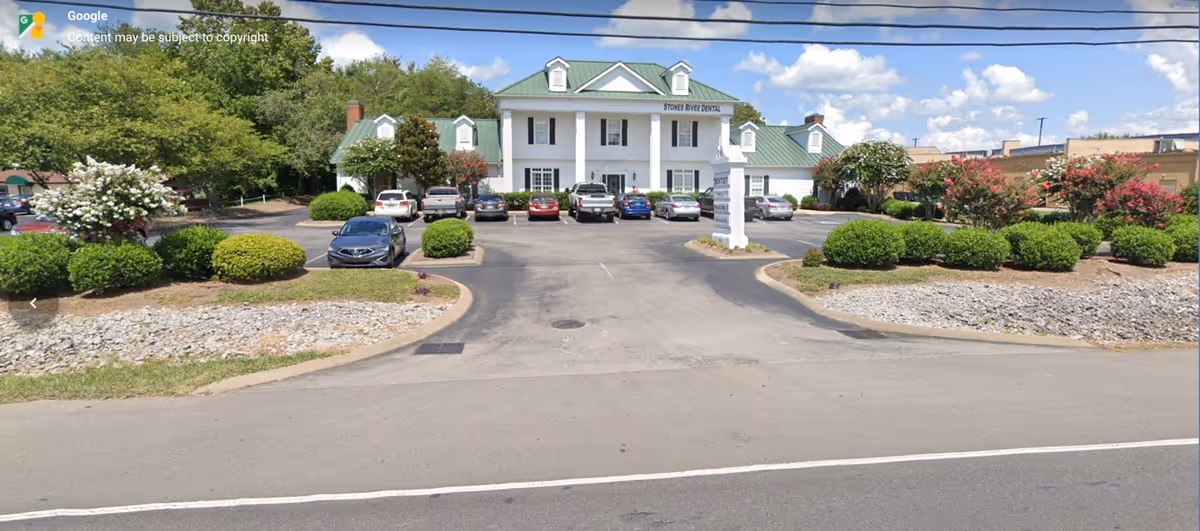 Front view of Synergy HomeCare facility with a parking lot and landscaped entrance.