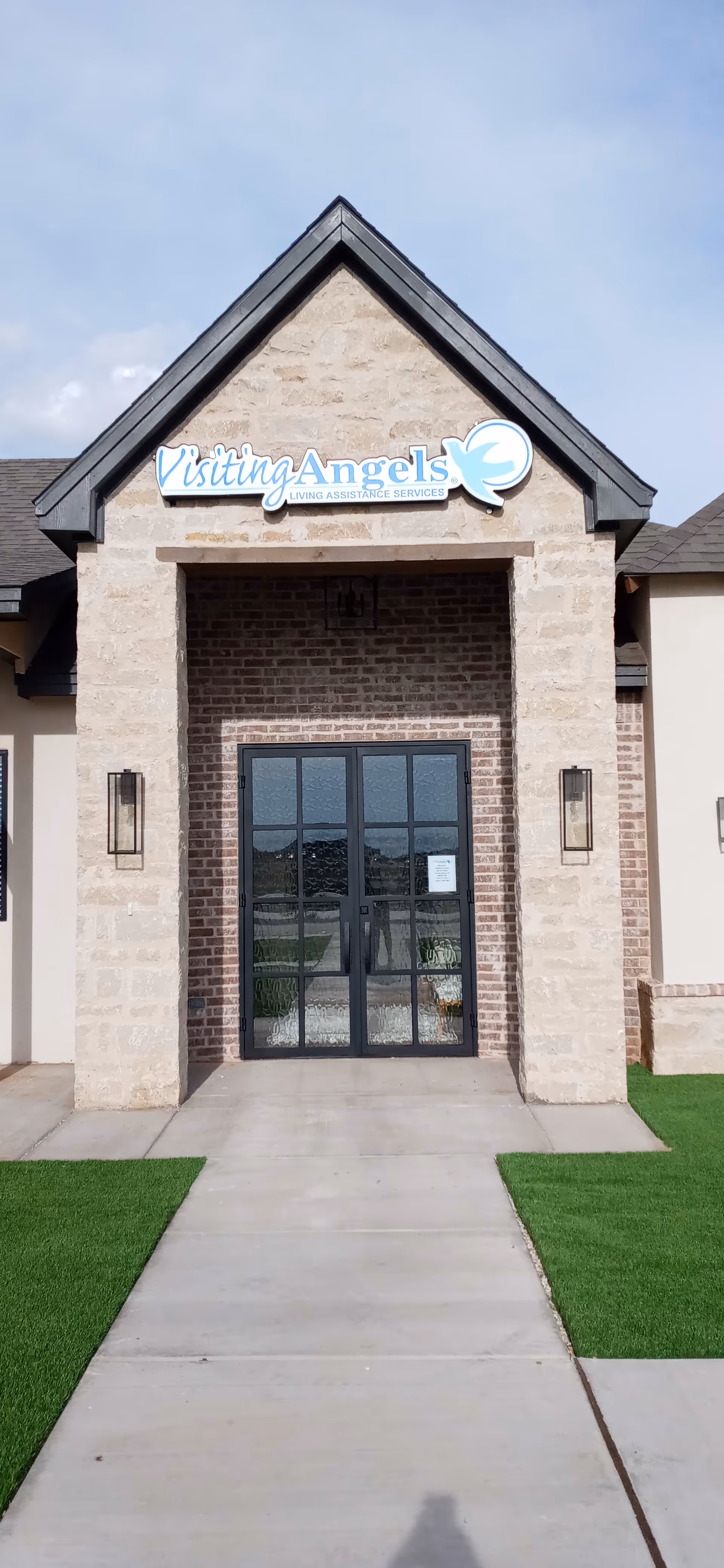 Front entrance of a Visiting Angels senior care facility with brick facade and glass doors.