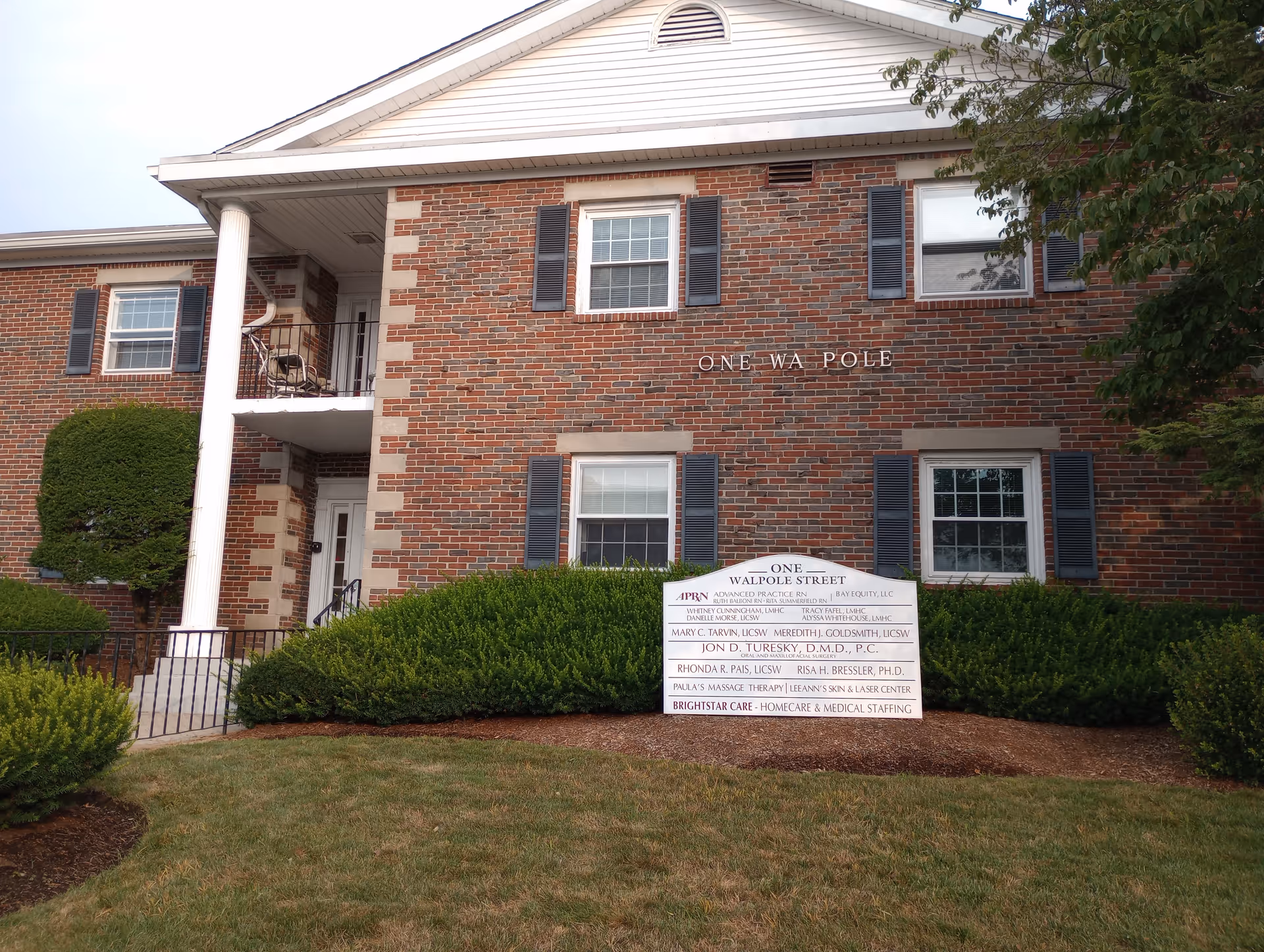 Brick senior living facility building with manicured lawn and a sign in front.