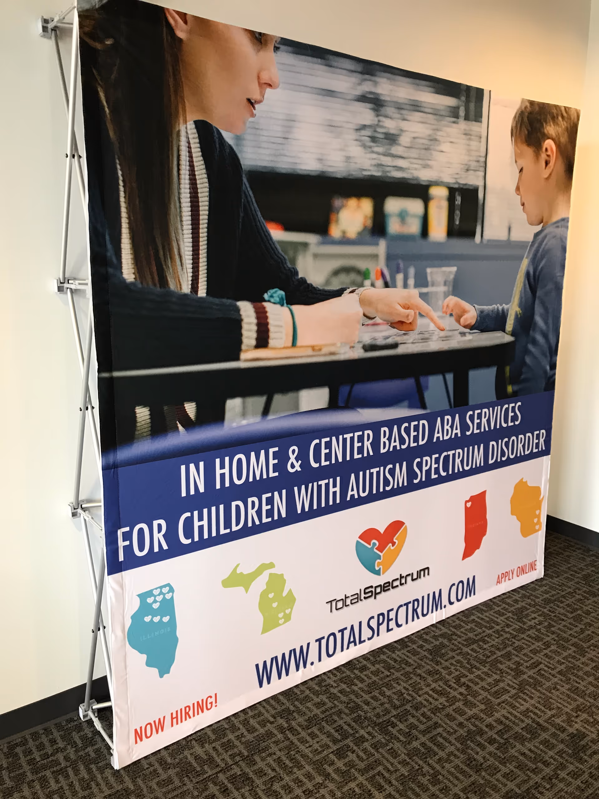 Large interior banner advertising Total Spectrum ABA services for children in a hallway.