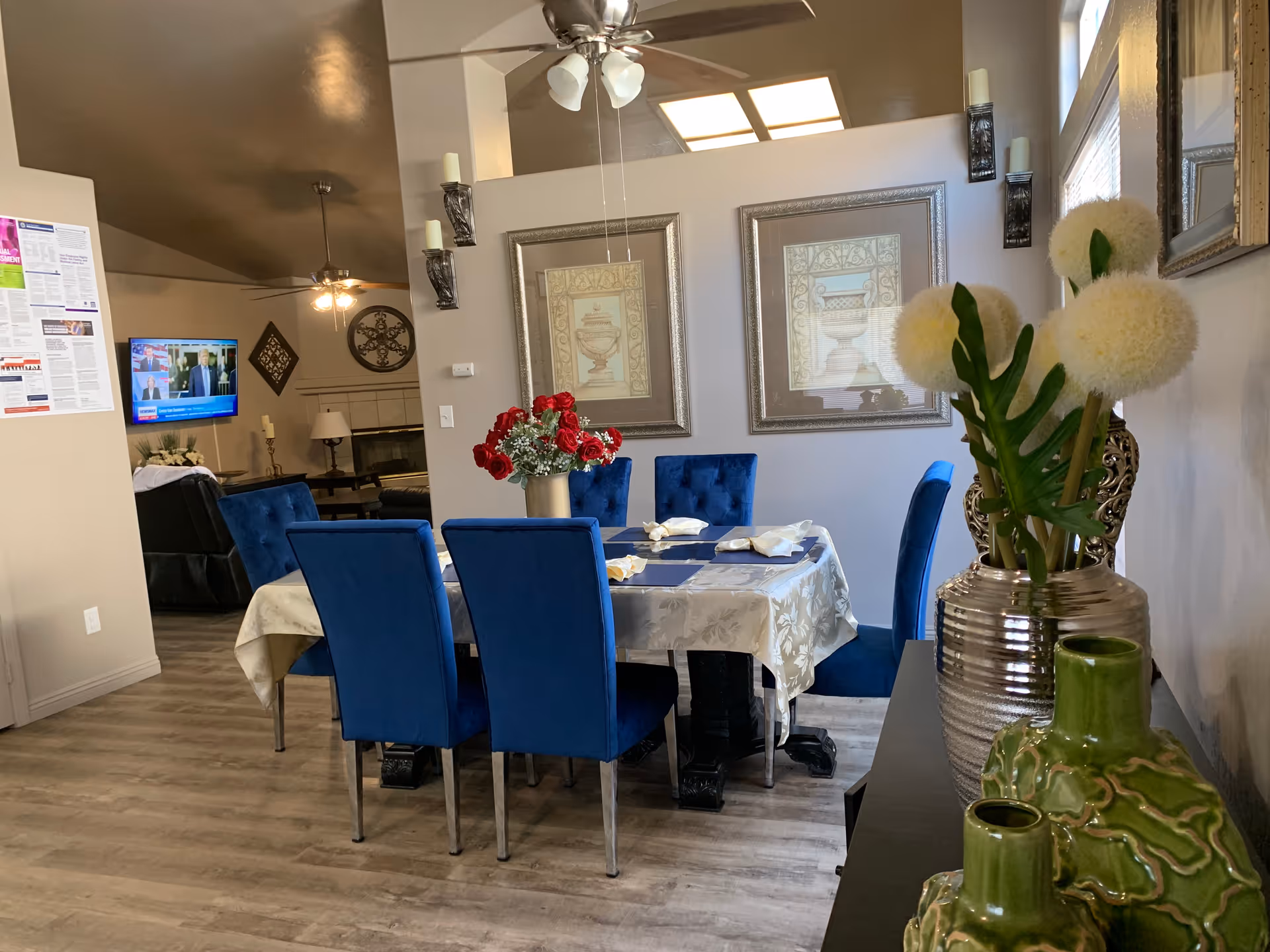 Blue upholstered dining chairs surround a table set with a floral centerpiece in a dining room.