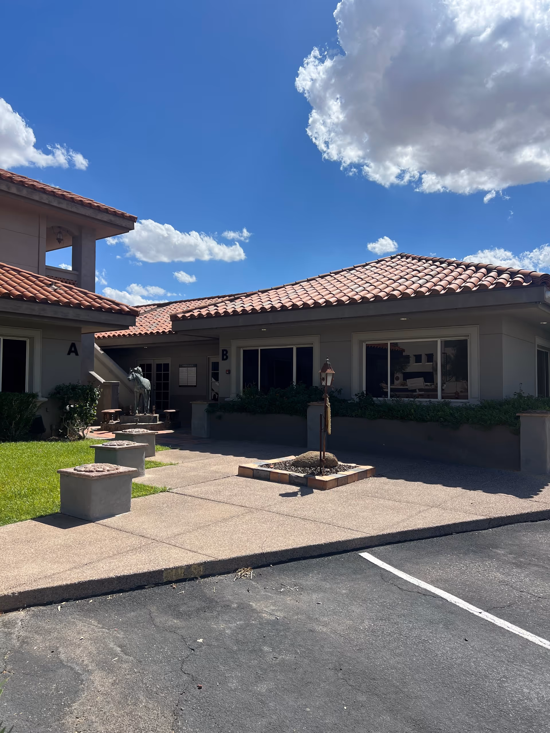 Exterior view of Heritage Home Care facility with tiled roof, courtyard, and parking lot.