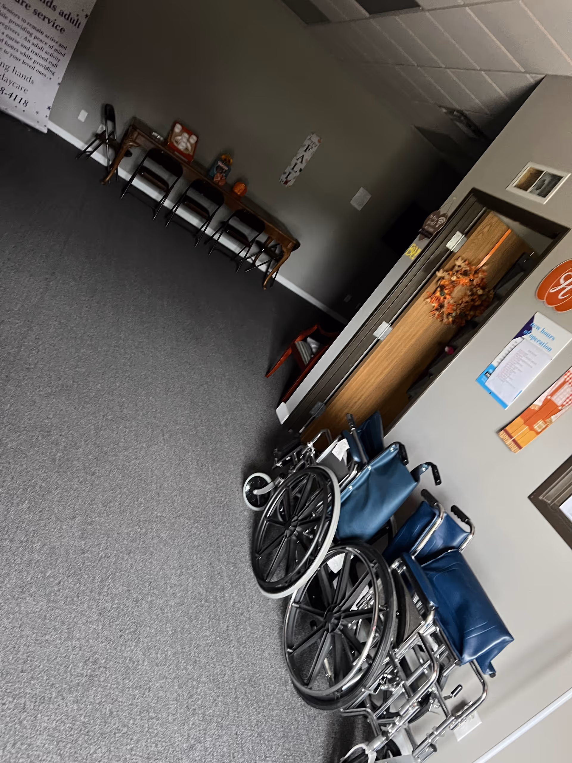 Wheelchairs and chairs lined up in a hallway of a senior care facility.