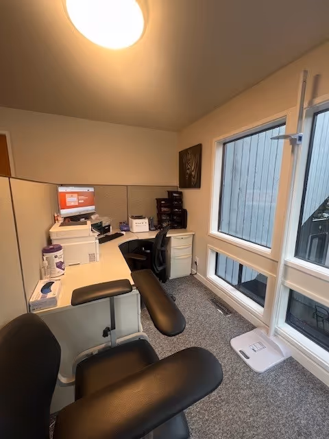 Small office in a facility with desks, chairs, computer, printer, and filing cabinets.