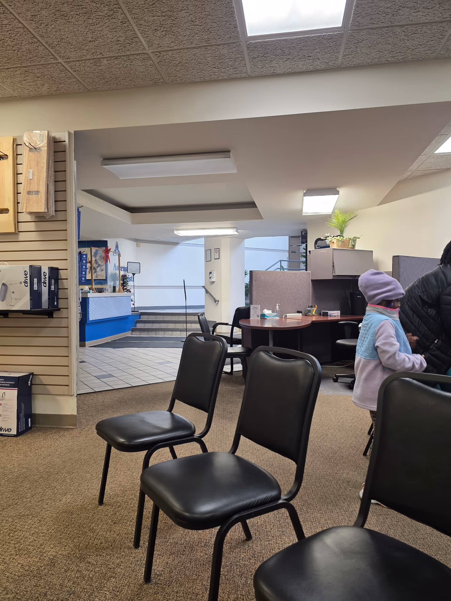 Interior waiting area with black chairs, a circular desk, and a reception counter in the background.
