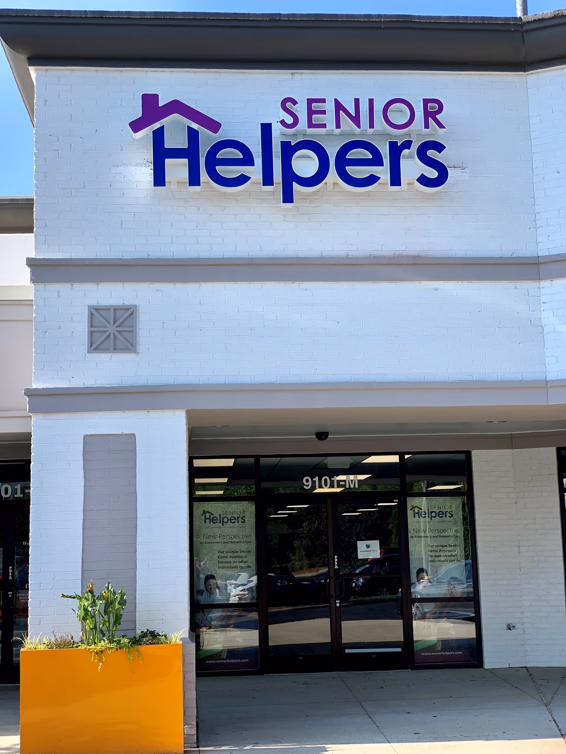 White brick building facade with Senior Helpers sign and glass entrance.