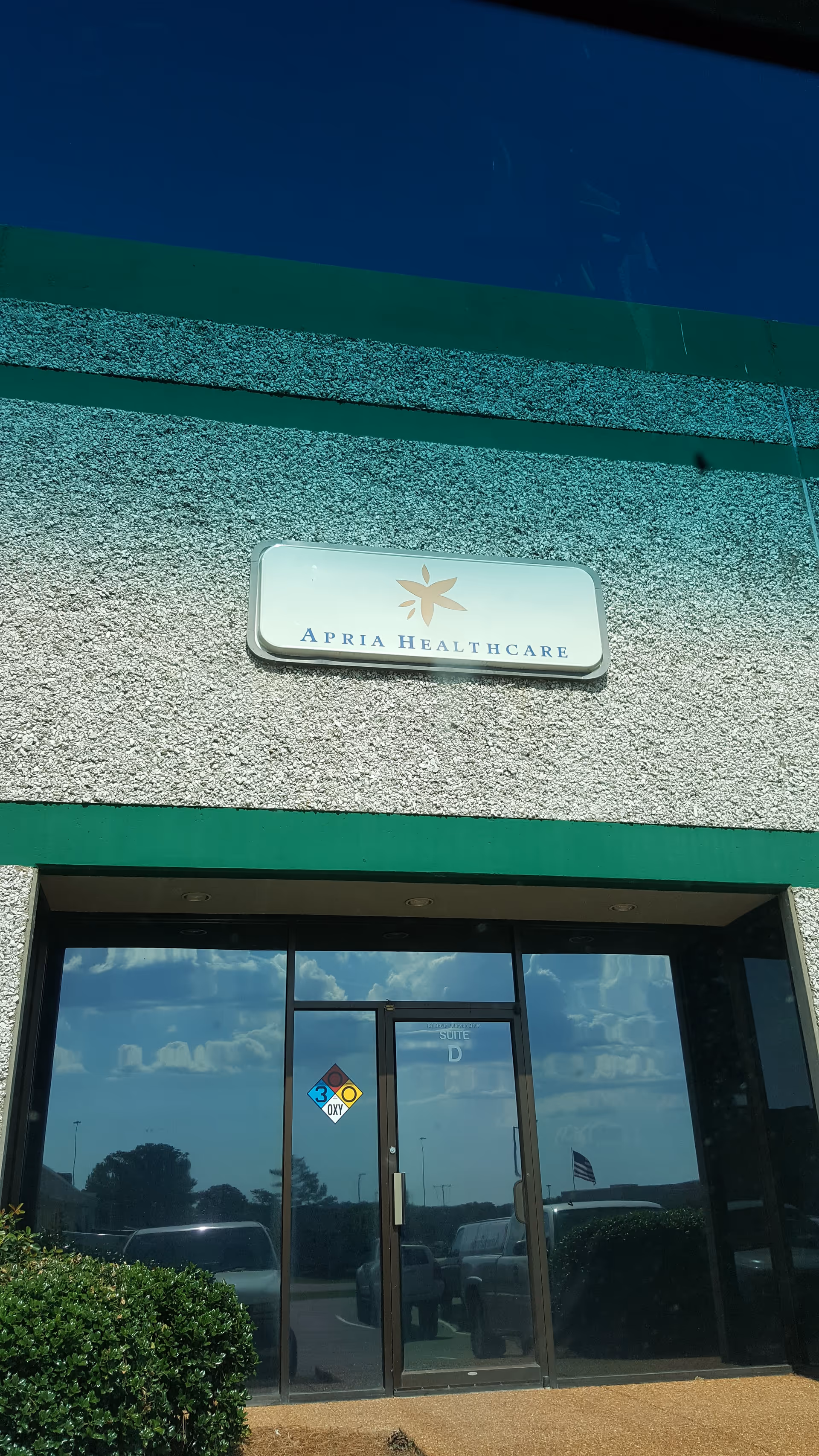Exterior view of Apria Healthcare building entrance with sign above glass doors.