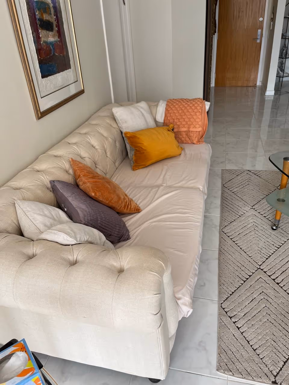 Cream tufted sofa with colorful cushions in a bright living area.
