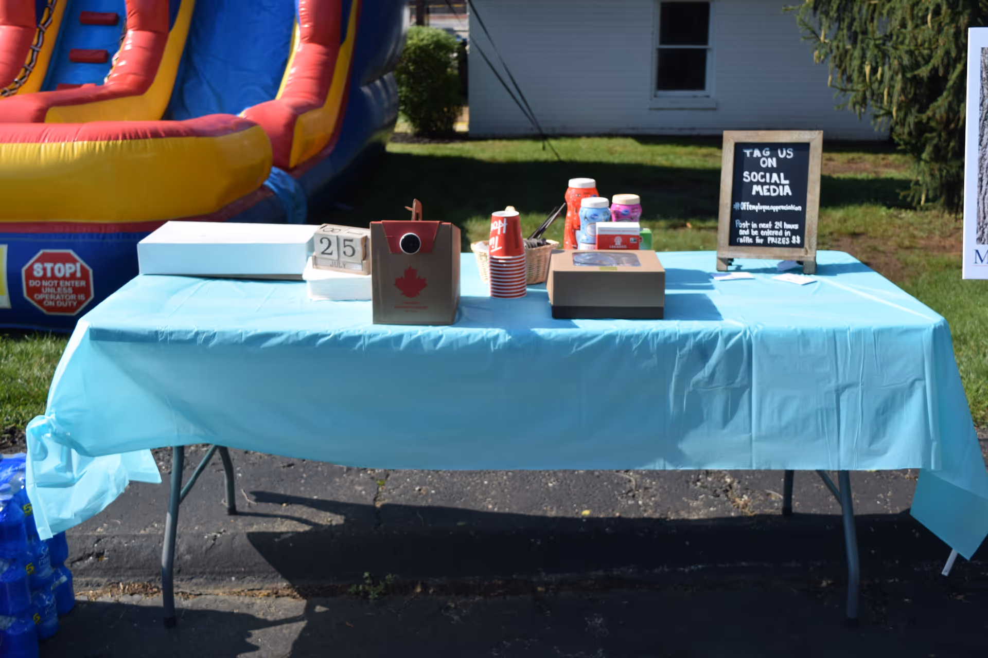Outdoor table with a blue cover and inflatable slide in background.