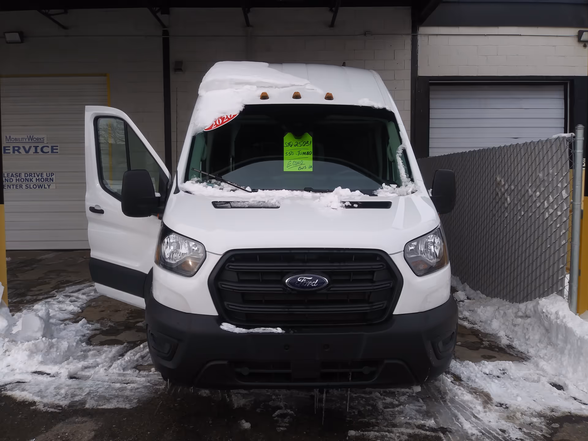 White van with snow on its hood in front of MobilityWorks service building.