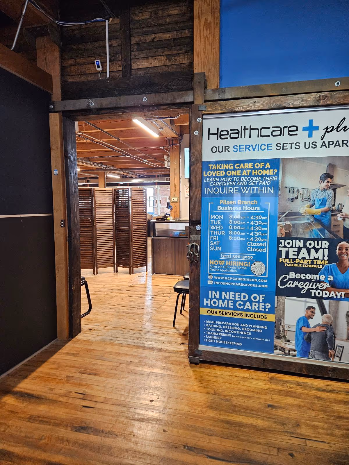 Interior hallway with wood floors and a large Healthcare Plus Caregivers signboard.