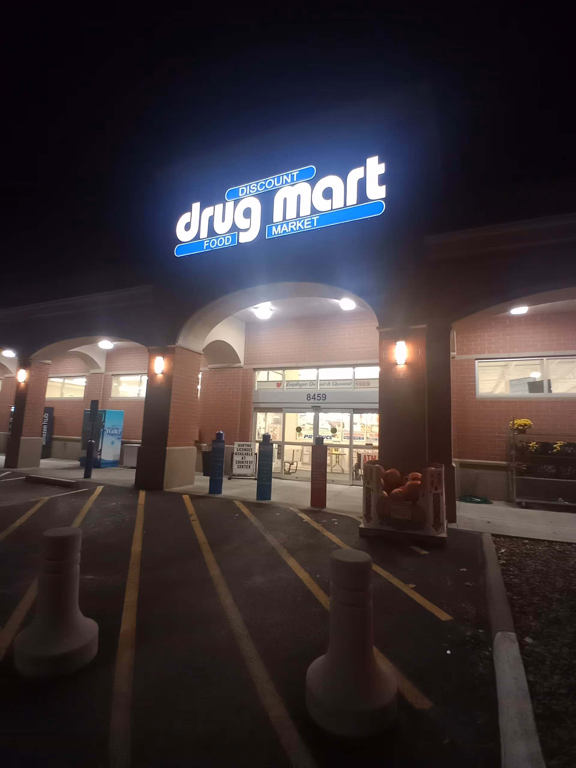 Nighttime exterior of Discount Drug Mart storefront with illuminated sign