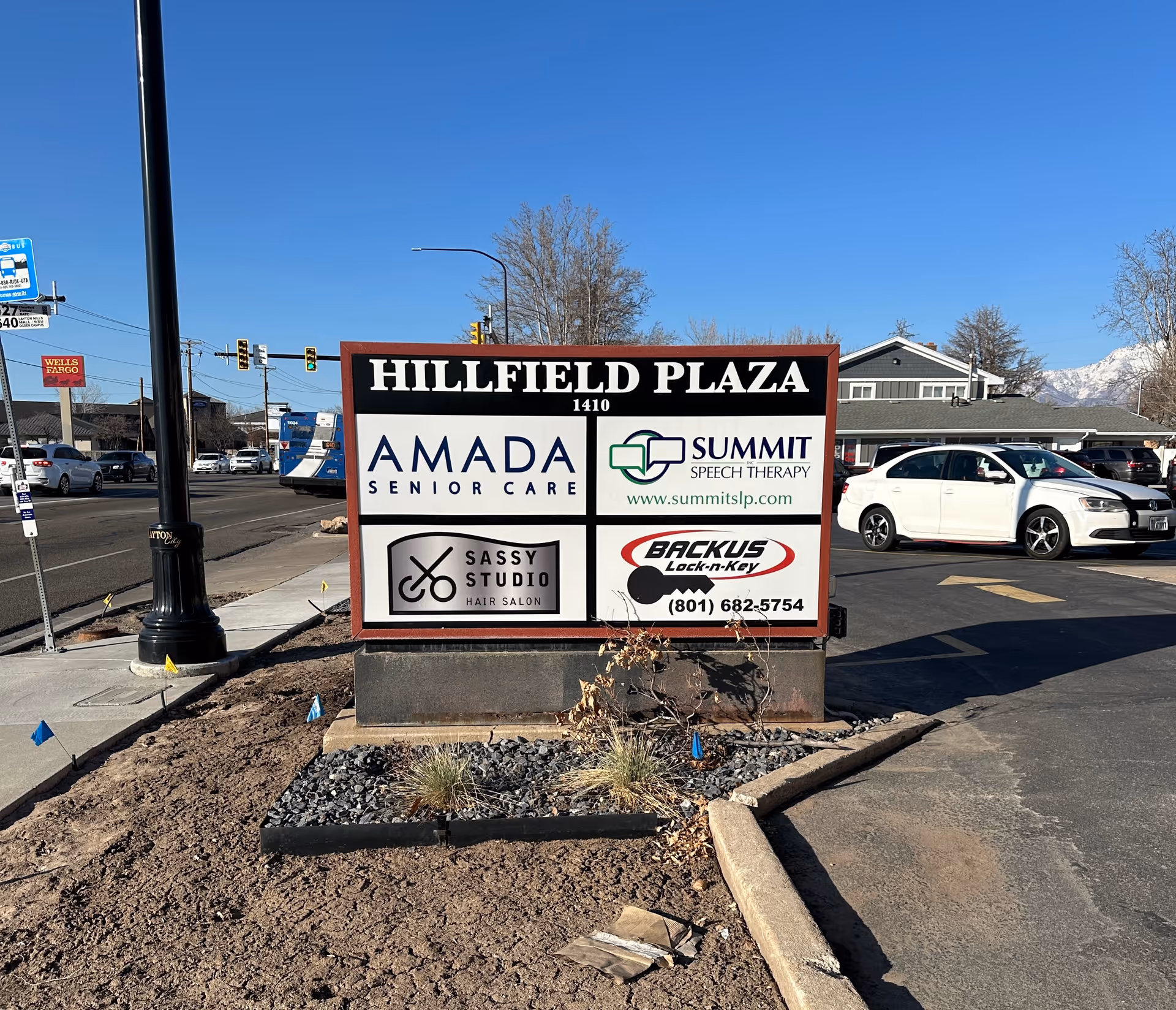 A large outdoor plaza sign displays Hillfield Plaza alongside Amada Senior Care logo.