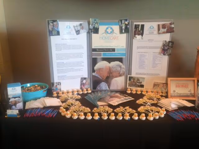 A display table with brochures and a large photo collage promoting No Place Like Home Care.