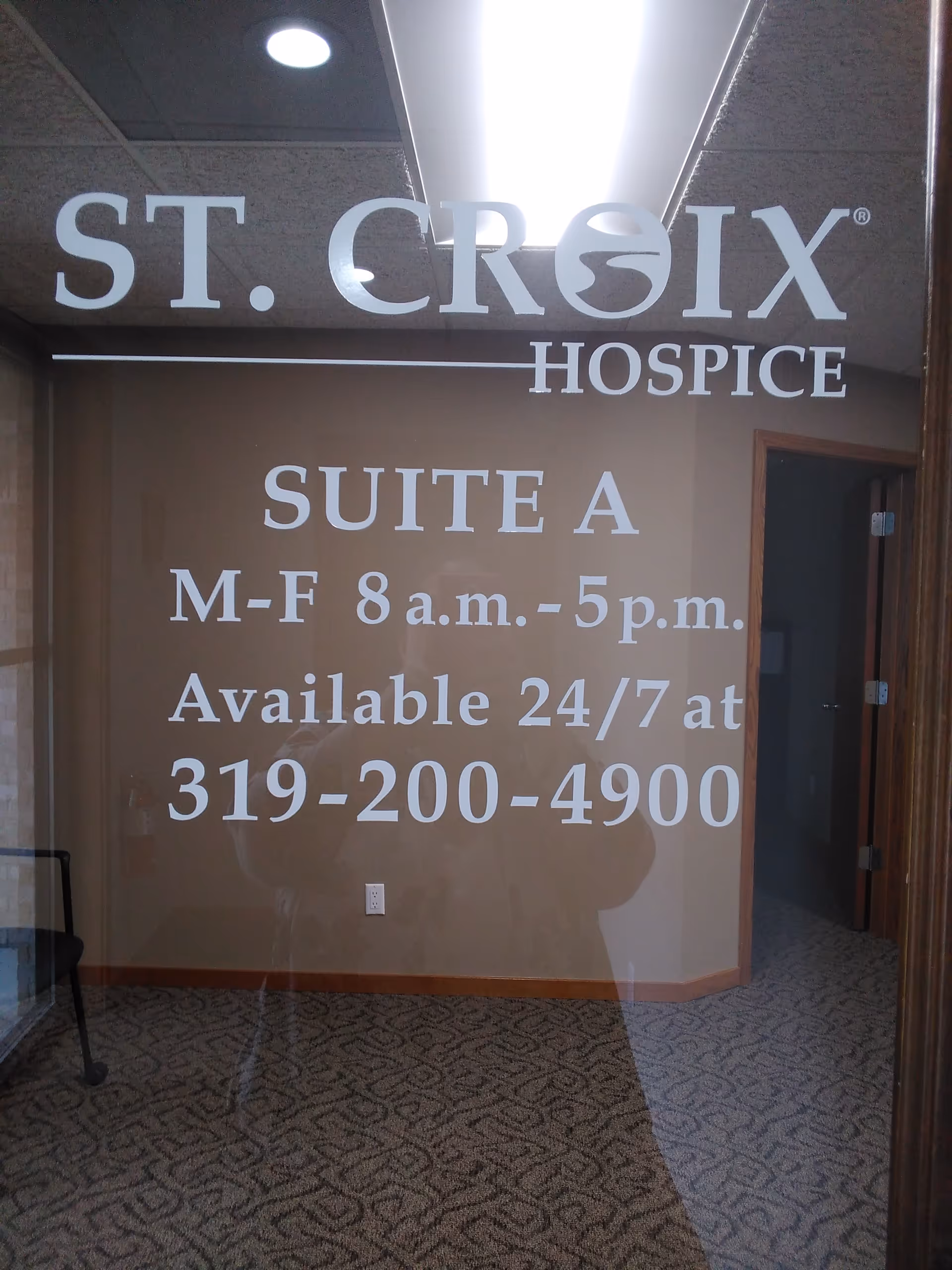 Glass door with ST. CROIX HOSPICE sign and Suite A hours