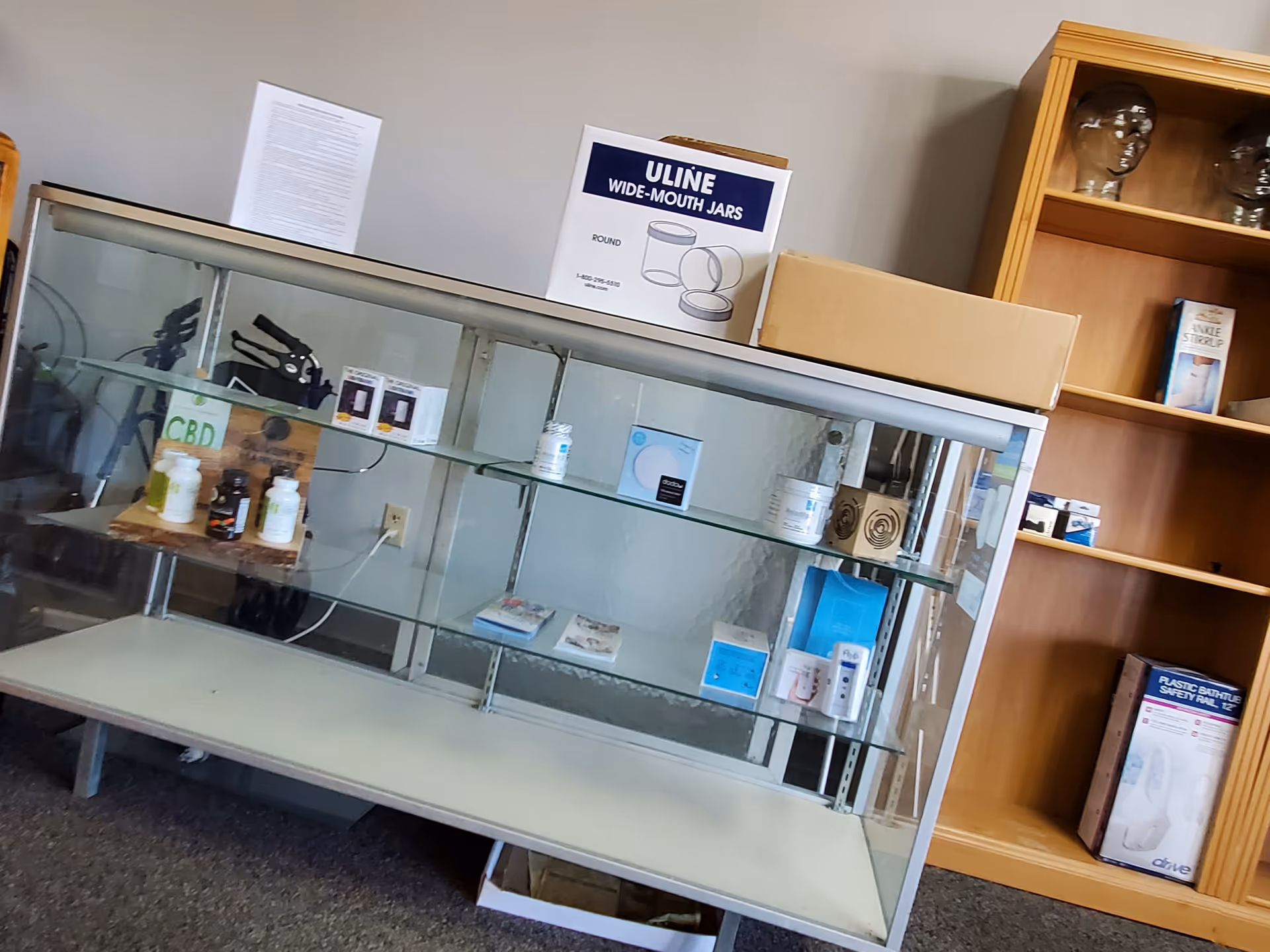 Empty glass display cabinet with medical supplies and shelves in a clinic room.