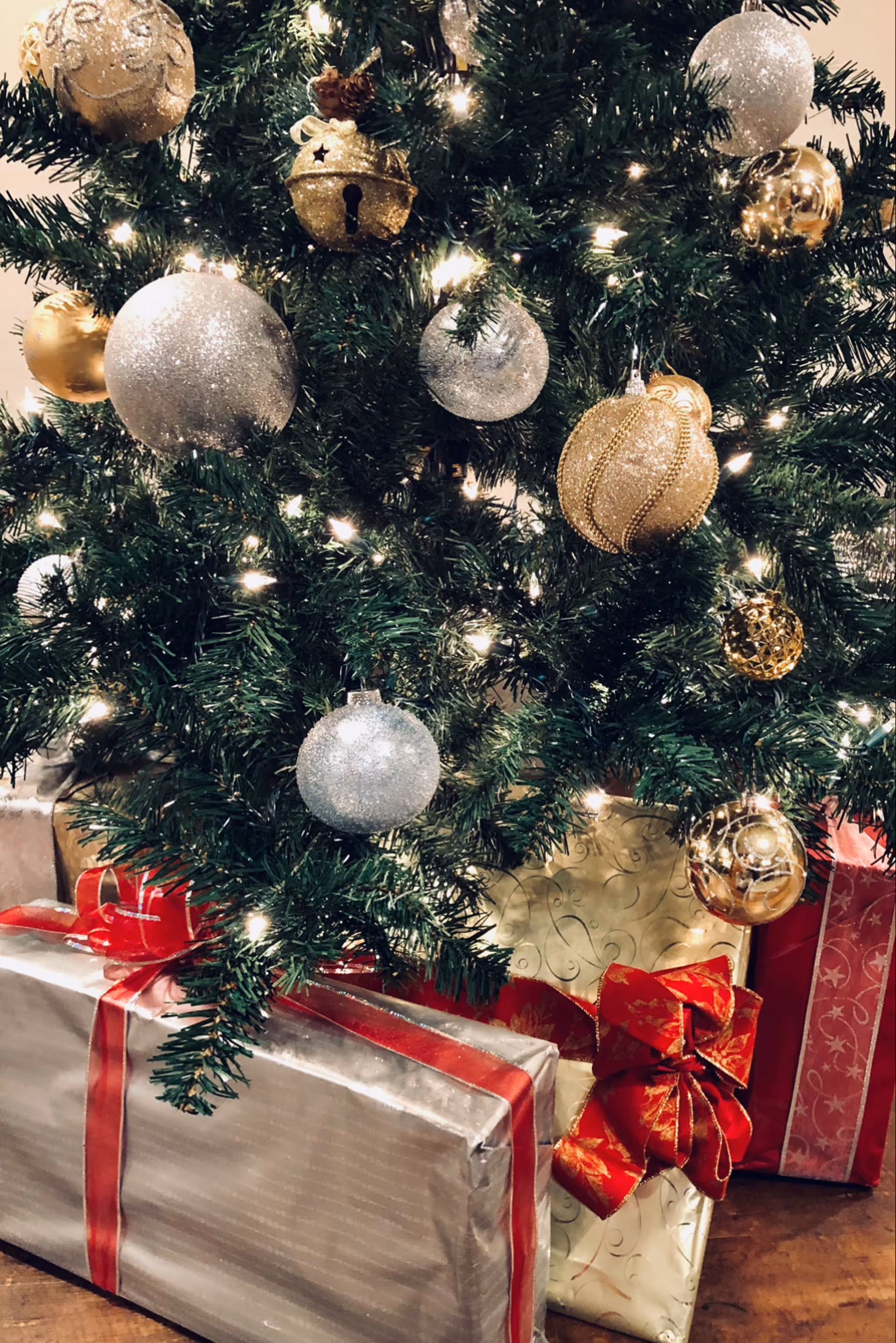 Indoor Christmas tree with gold and silver ornaments and wrapped presents.